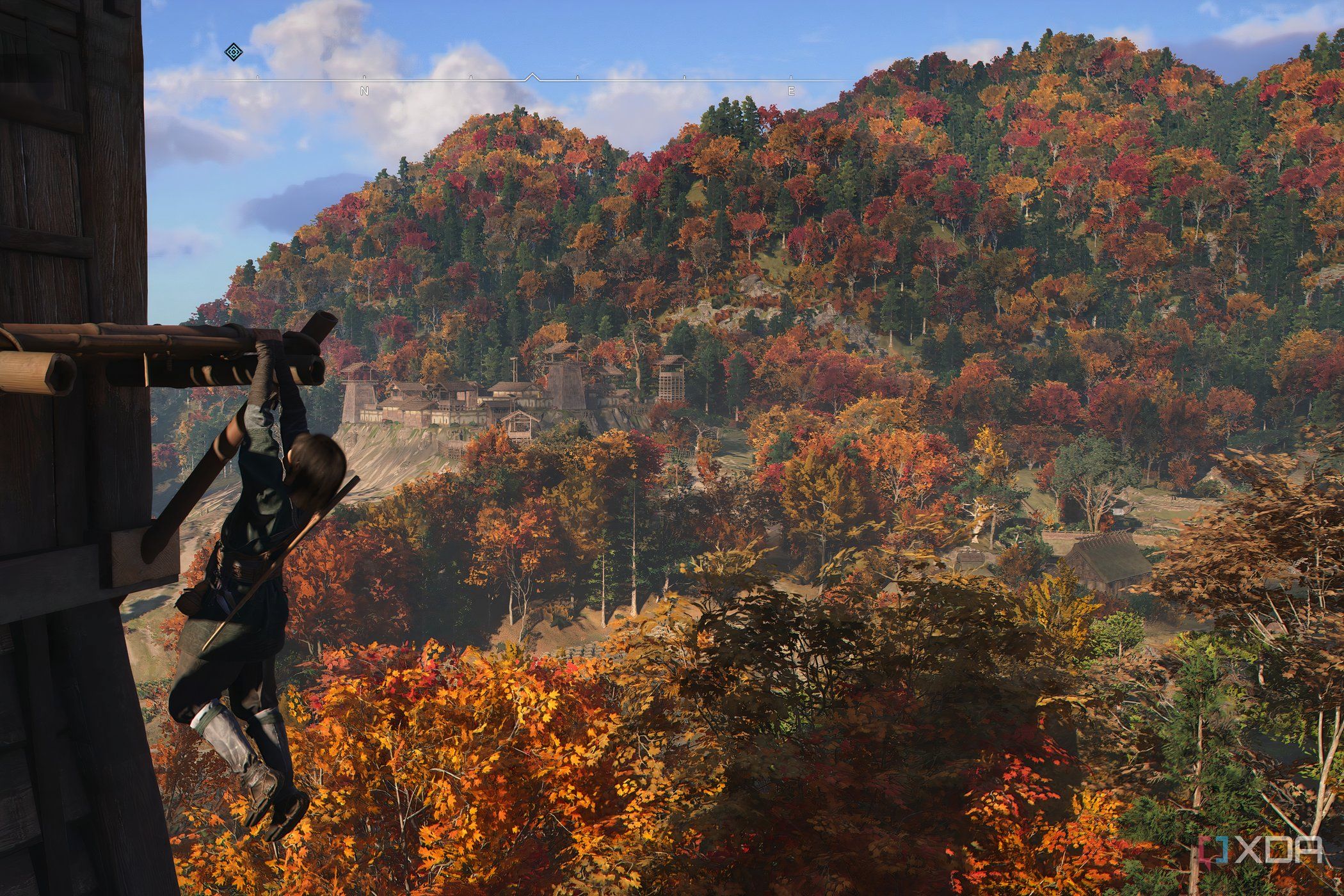 A screenshot from the game Assassin's Creed Shadows, showing Naoe, the protagonist, hanging from a wooden ledge.