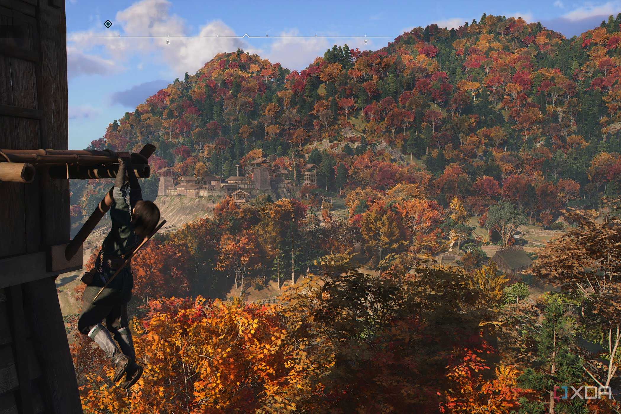 A screenshot from the game Assassin's Creed Shadows, showing Naoe, the protagonist, hanging from a wooden ledge.