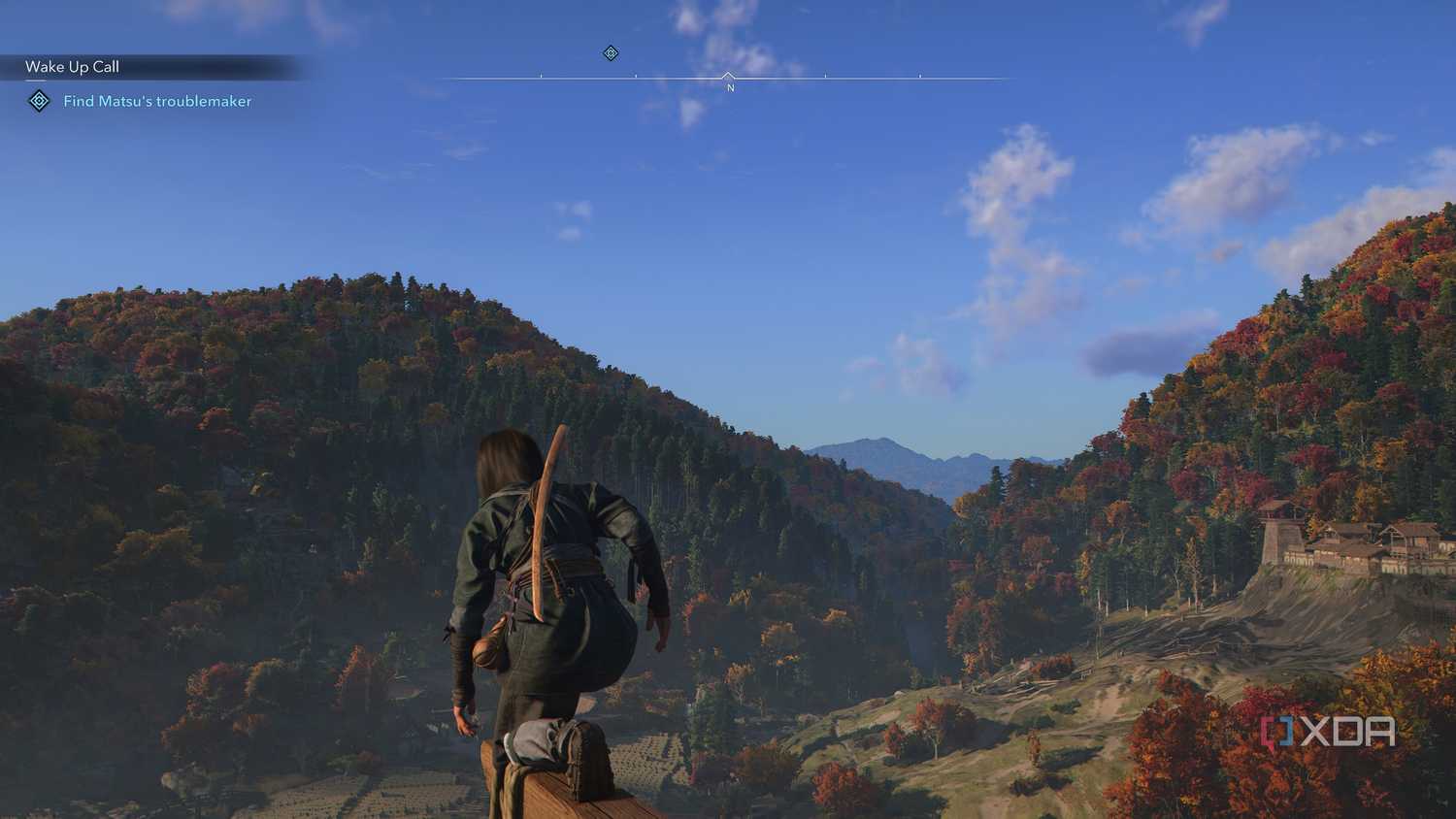 A screenshot from Assassin's Creed Shadows, showing Naoe, the female protagonist, perched atop a wooden beam, taking in the densely vegetated mountains.
