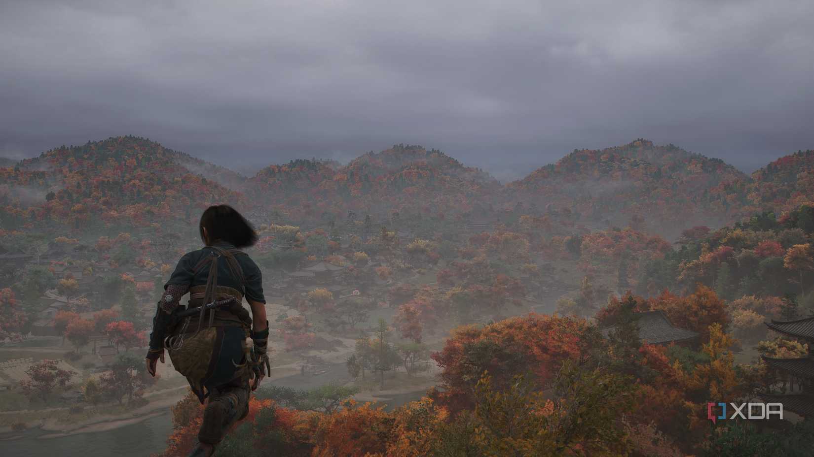 A screenshot from Assassin's Creed Shadows, showing Naoe, the female protagonist, perched atop somewhere high as the winds blow.