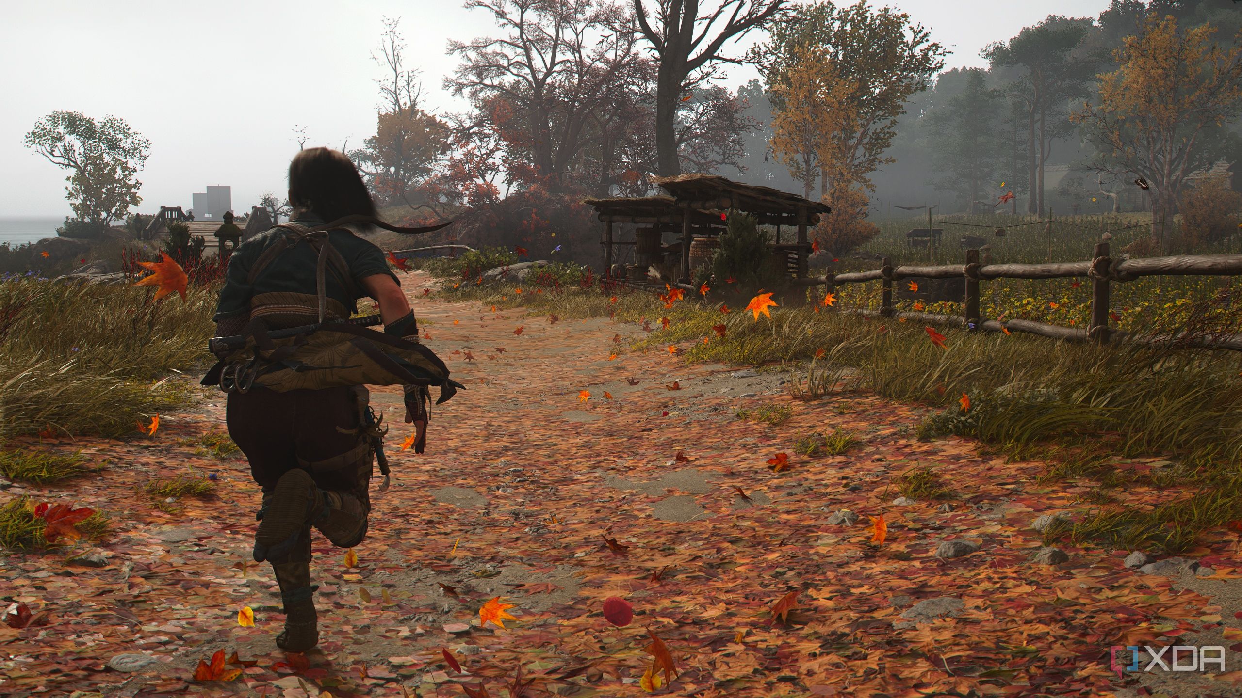 A screenshot from Assassin's Creed Shadows, showing Naoe, the female protagonist, running on a dirt road covered in fallen leaves.