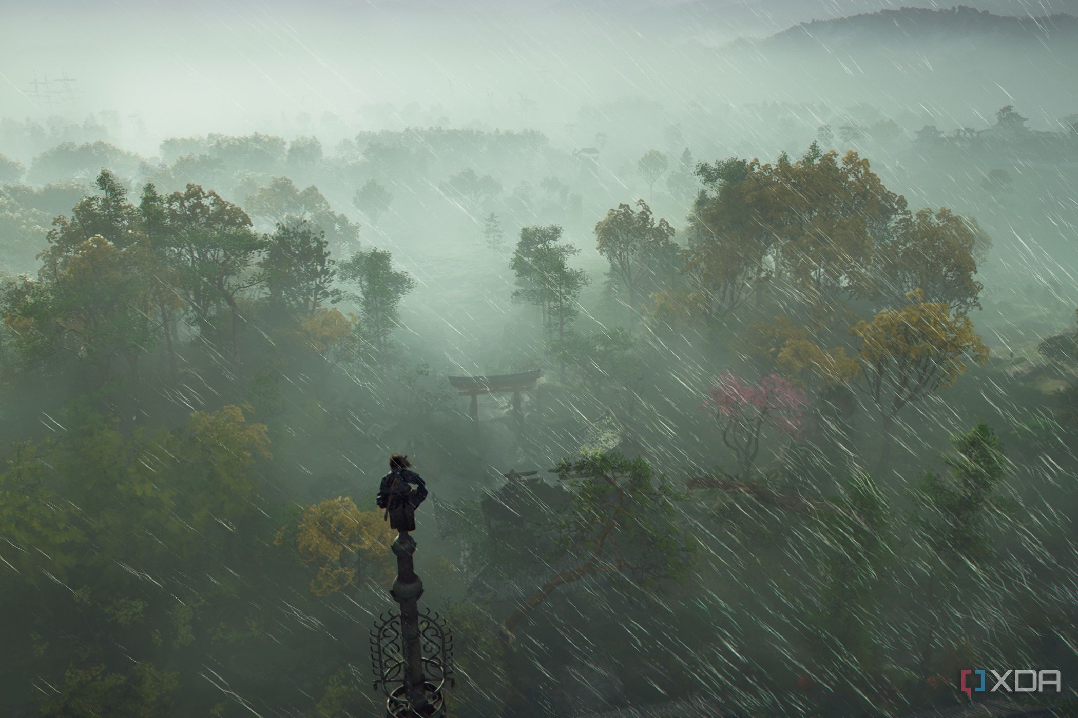 A screenshot from Assassin's Creed Shadows, showing Naoe, the protagonist, perched atop a tall pillar as rain sweeps around her.