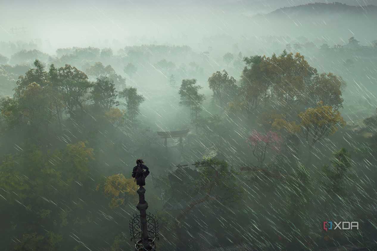 A screenshot from Assassin's Creed Shadows, showing Naoe, the protagonist, perched atop a tall pillar as rain sweeps around her.
