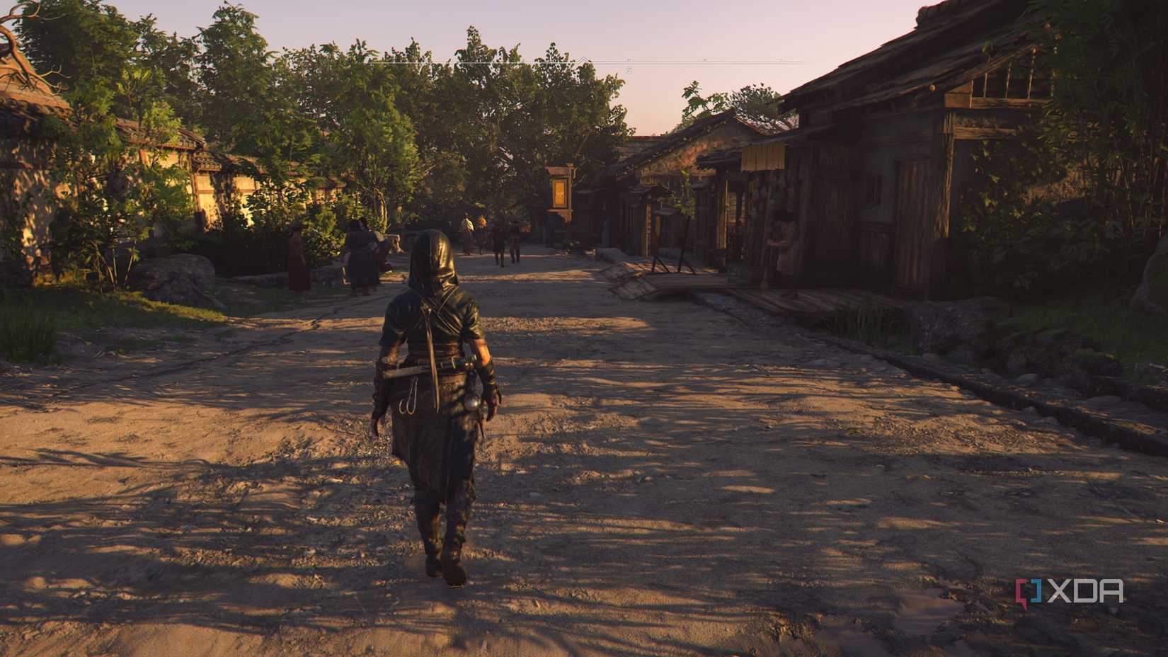 A screenshot from Assassin's Creed Shadows, showing a hooded woman in wet clothes walking through a street.