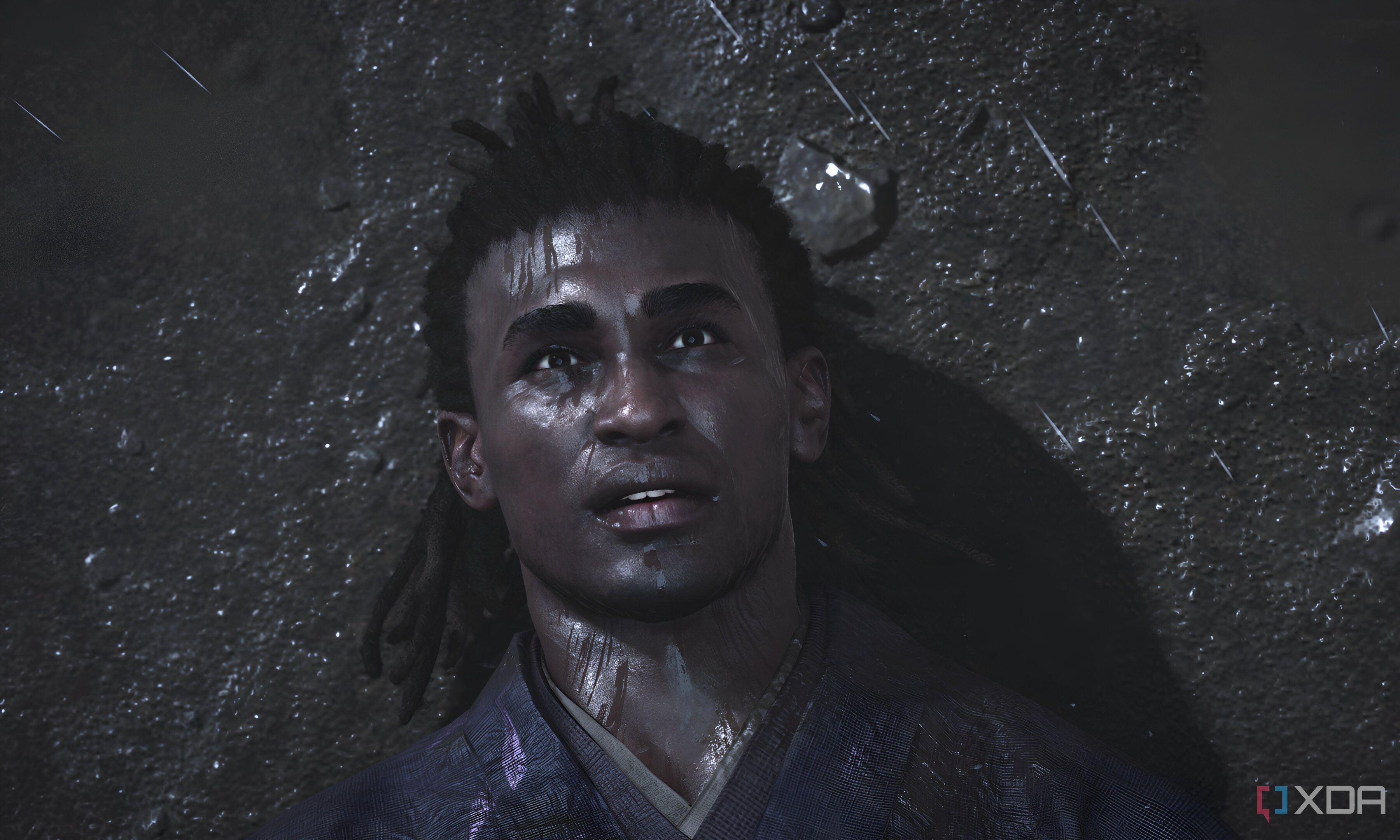 A screenshot from Assassin's Creed Shadows, showing Yasuke, the protagonist, laying on the ground as it rains.