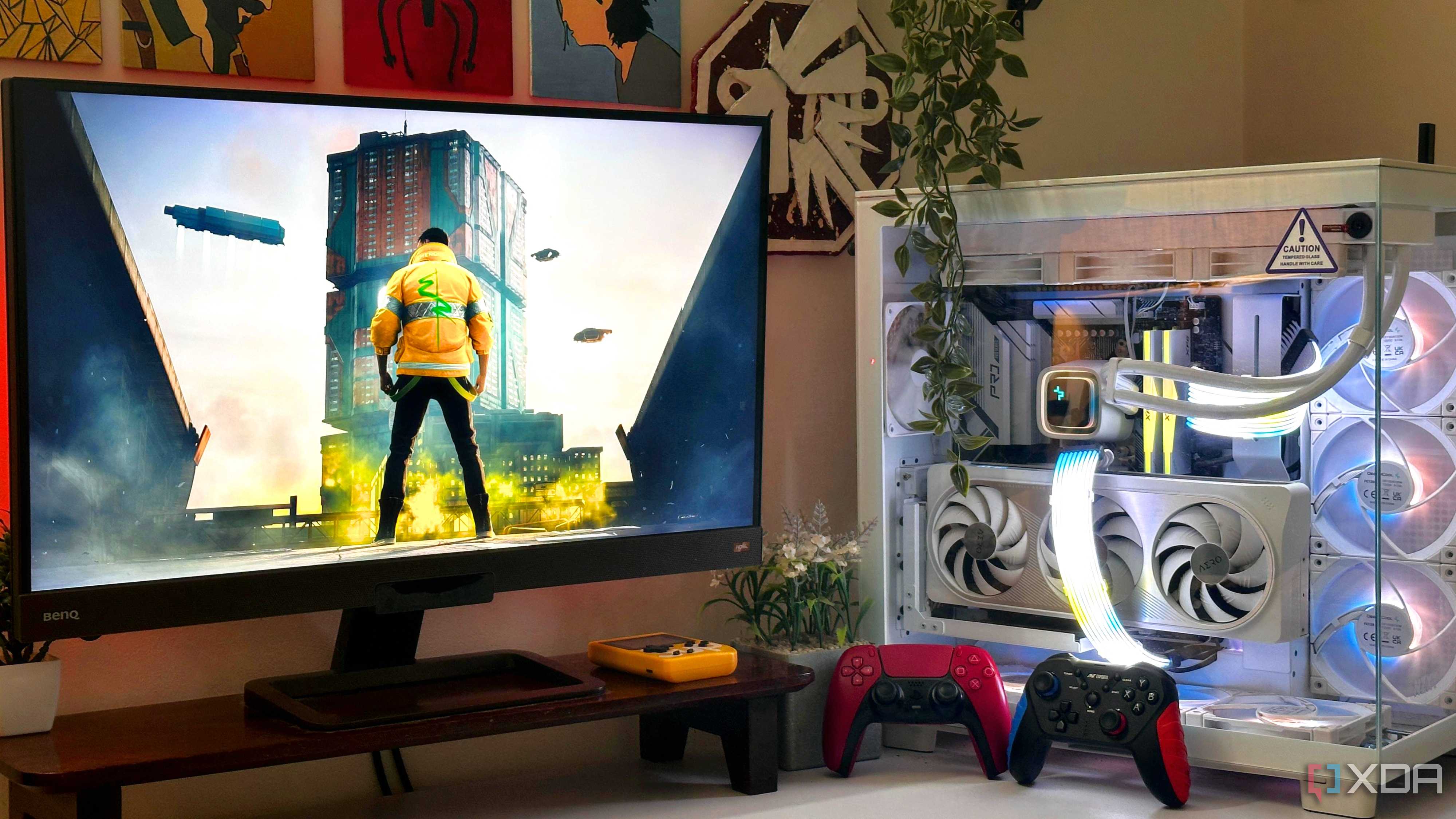 An image showing a PC setup with Cyberpunk 2077 on the monitor, and two gaming controllers resting against the PC case.
