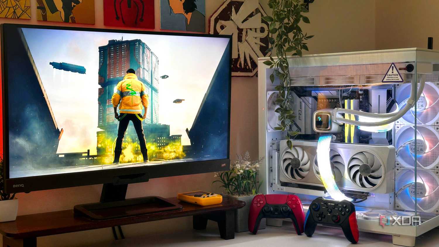 An image showing a PC setup with Cyberpunk 2077 on the monitor, and two gaming controllers resting against the PC case.
