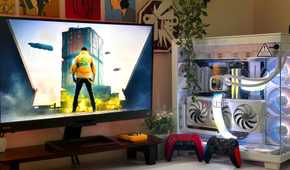 An image showing a PC setup with Cyberpunk 2077 on the monitor, and two gaming controllers resting against the PC case.