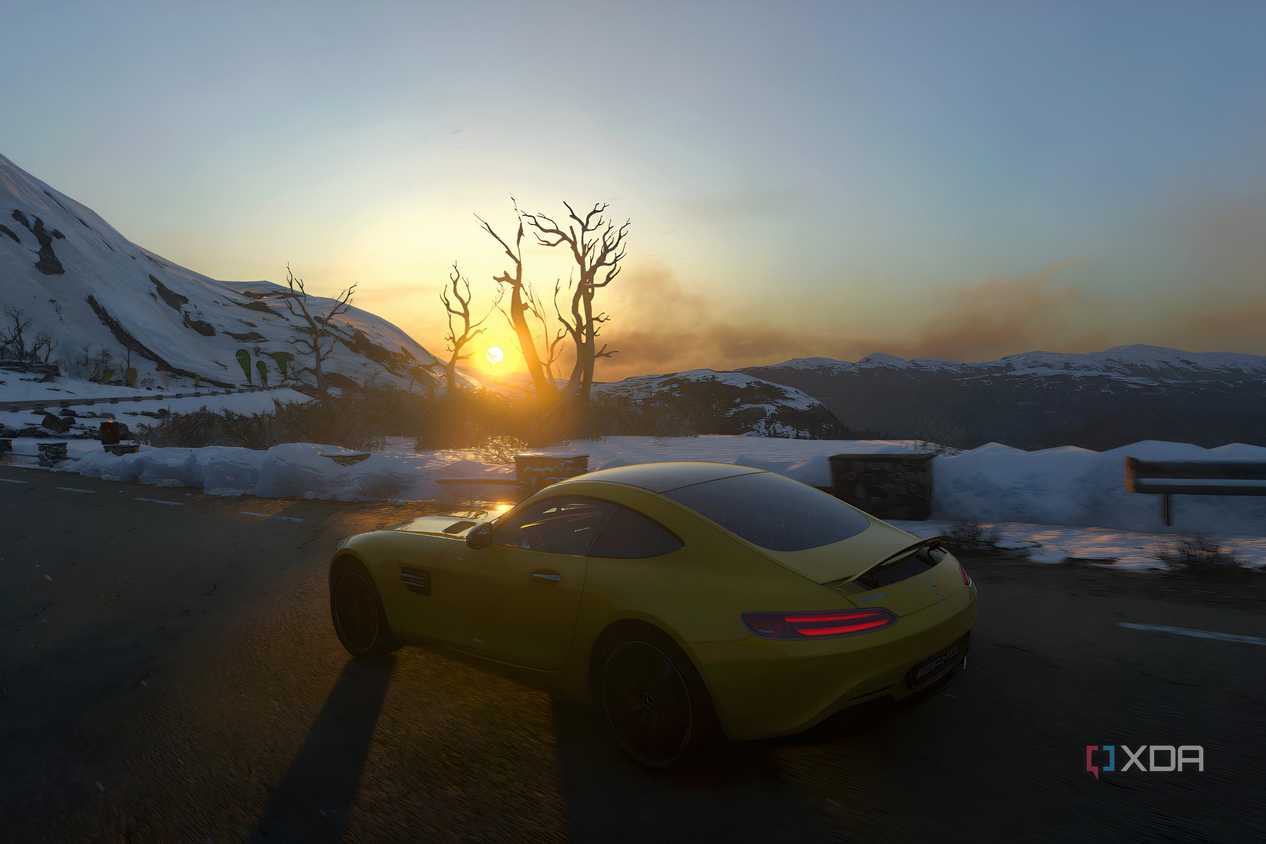 An image from the 2014 game Driveclub, showing a yellow Mercedes car frmo the side, driving in a snowy setting as the sun rises.