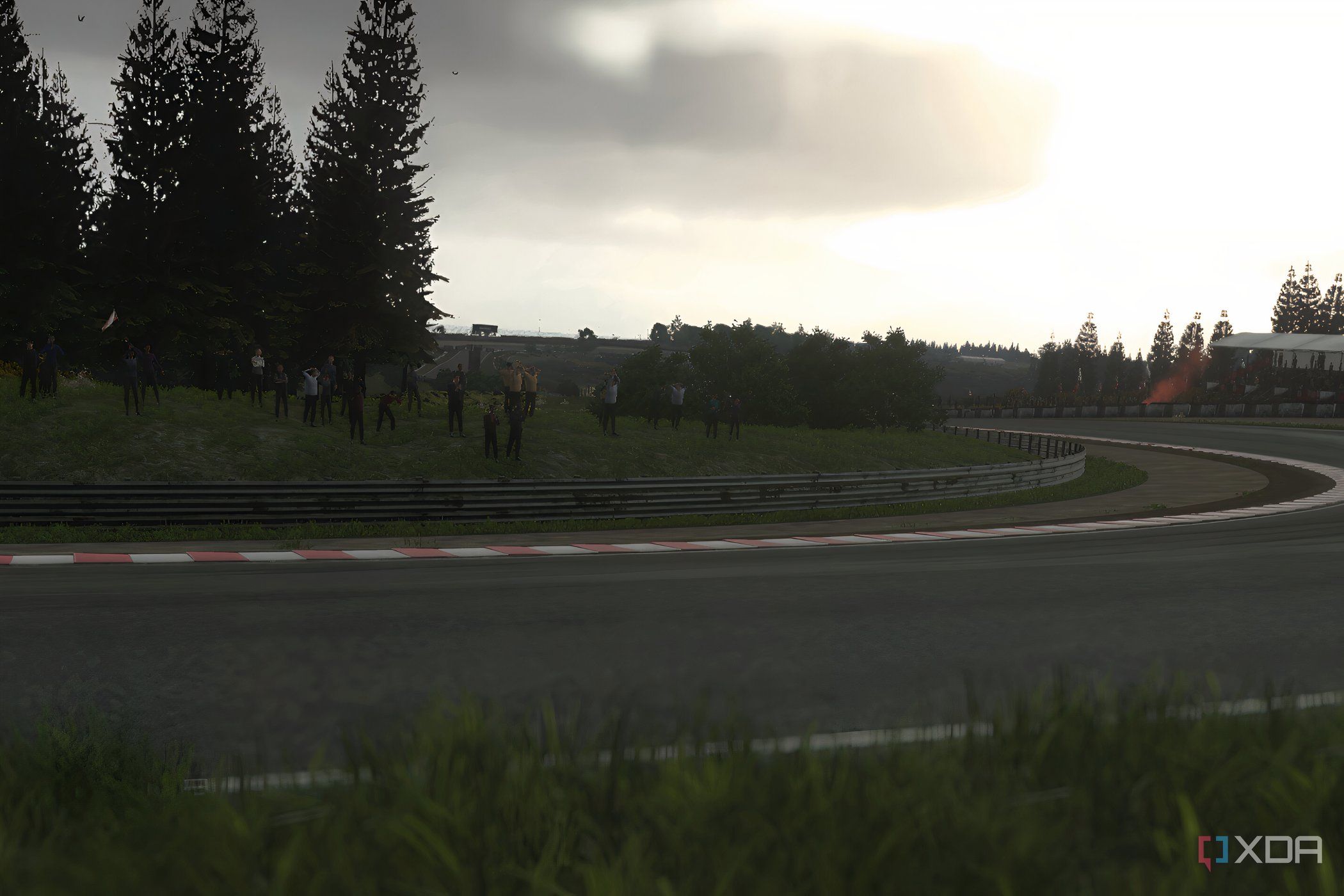 An image from the 2014 game Driveclub, showing a sunlit winding track with grass fields around it.