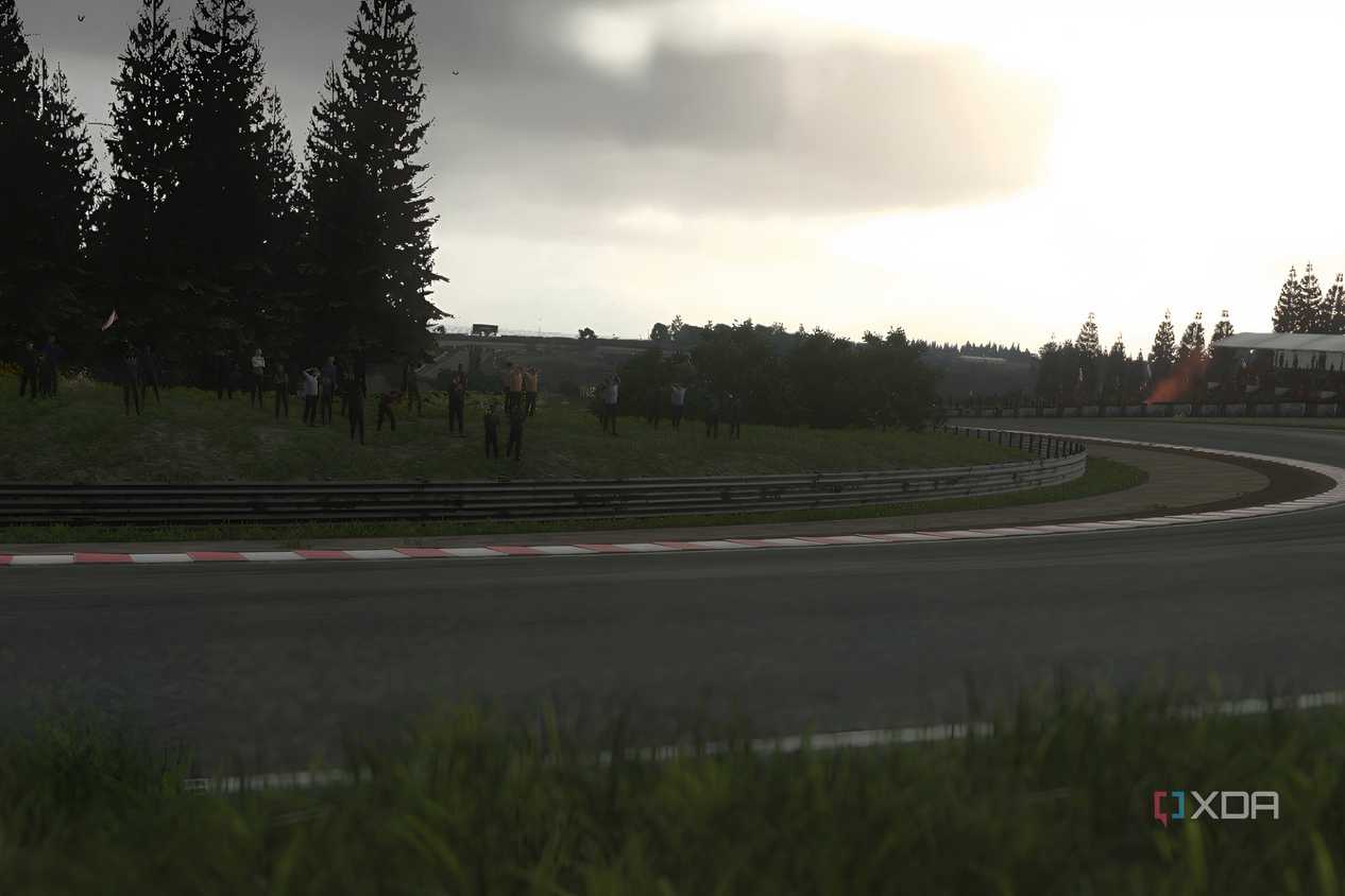 An image from the 2014 game Driveclub, showing a sunlit winding track with grass fields around it.