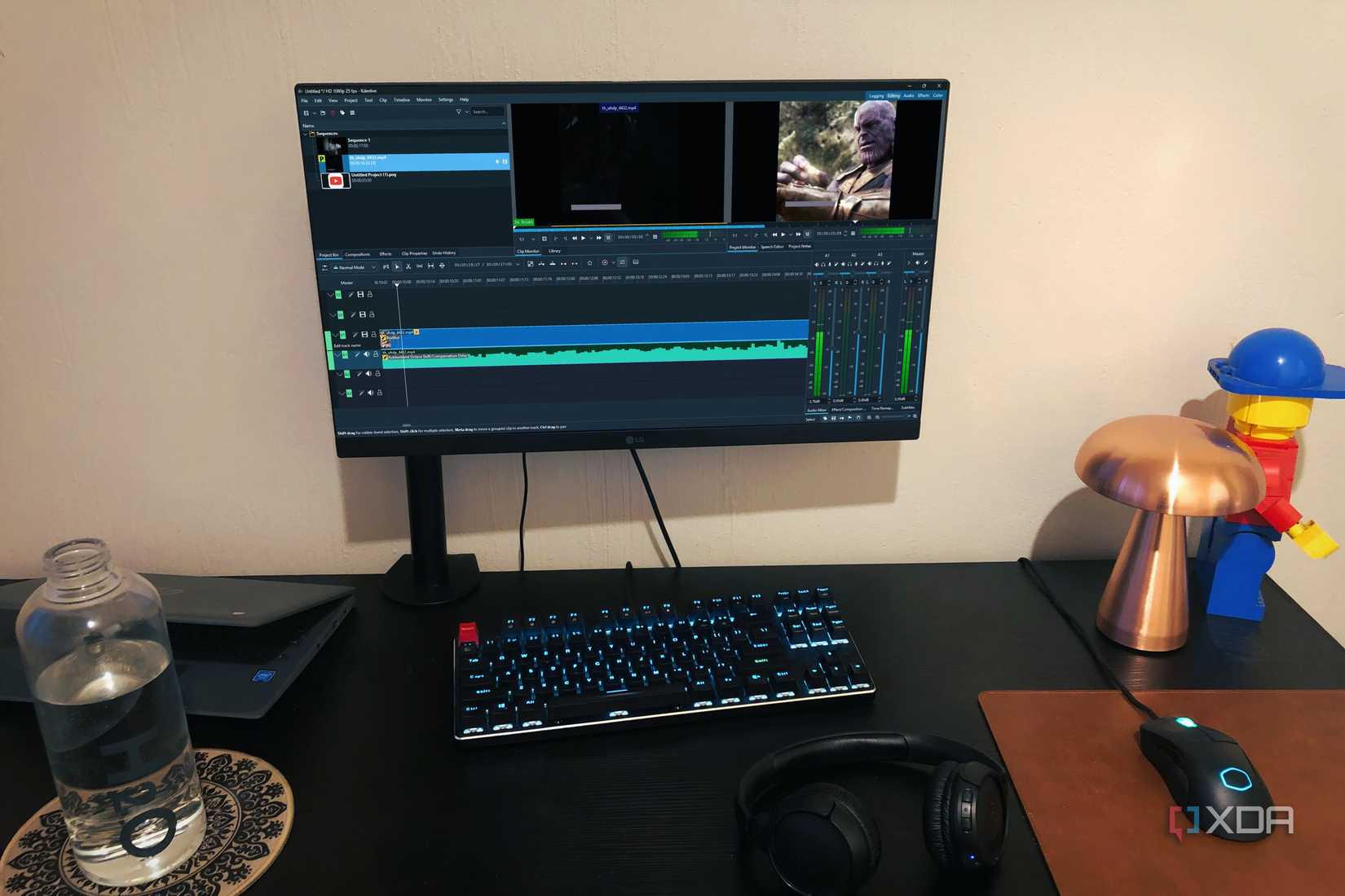 Kdenlive shown on a PC desktop, with a lamp, a bottle, a lego and a Chromebook in view