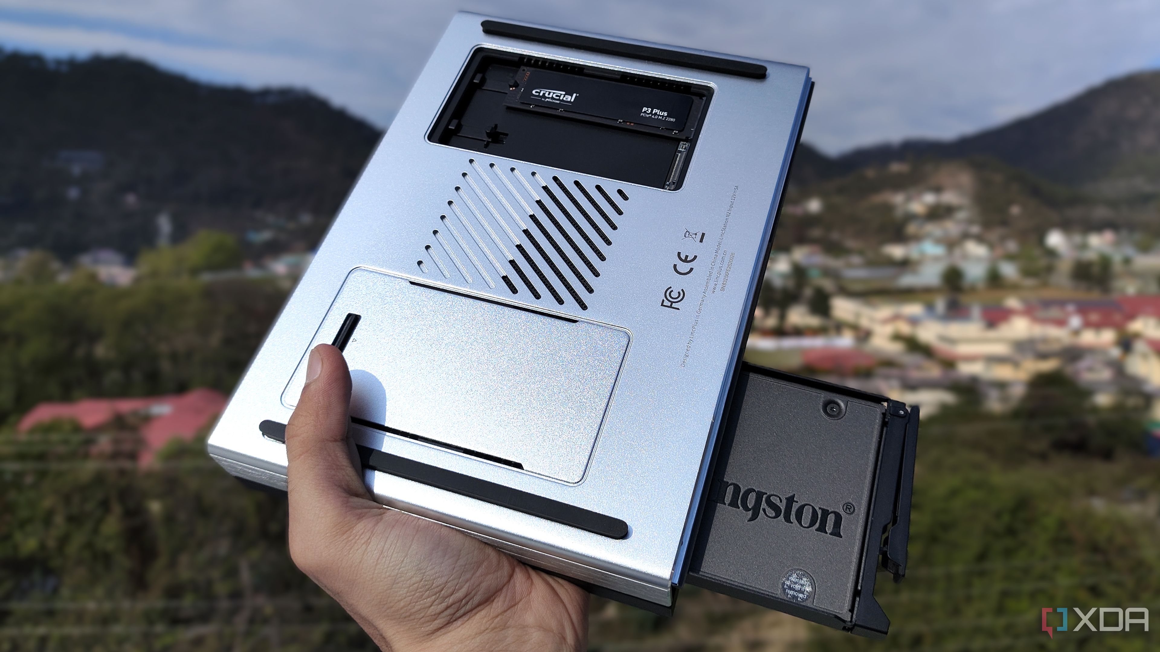 A person holding the LincPlus LincStation N2 NAS, with an SSD popping out of the NAS