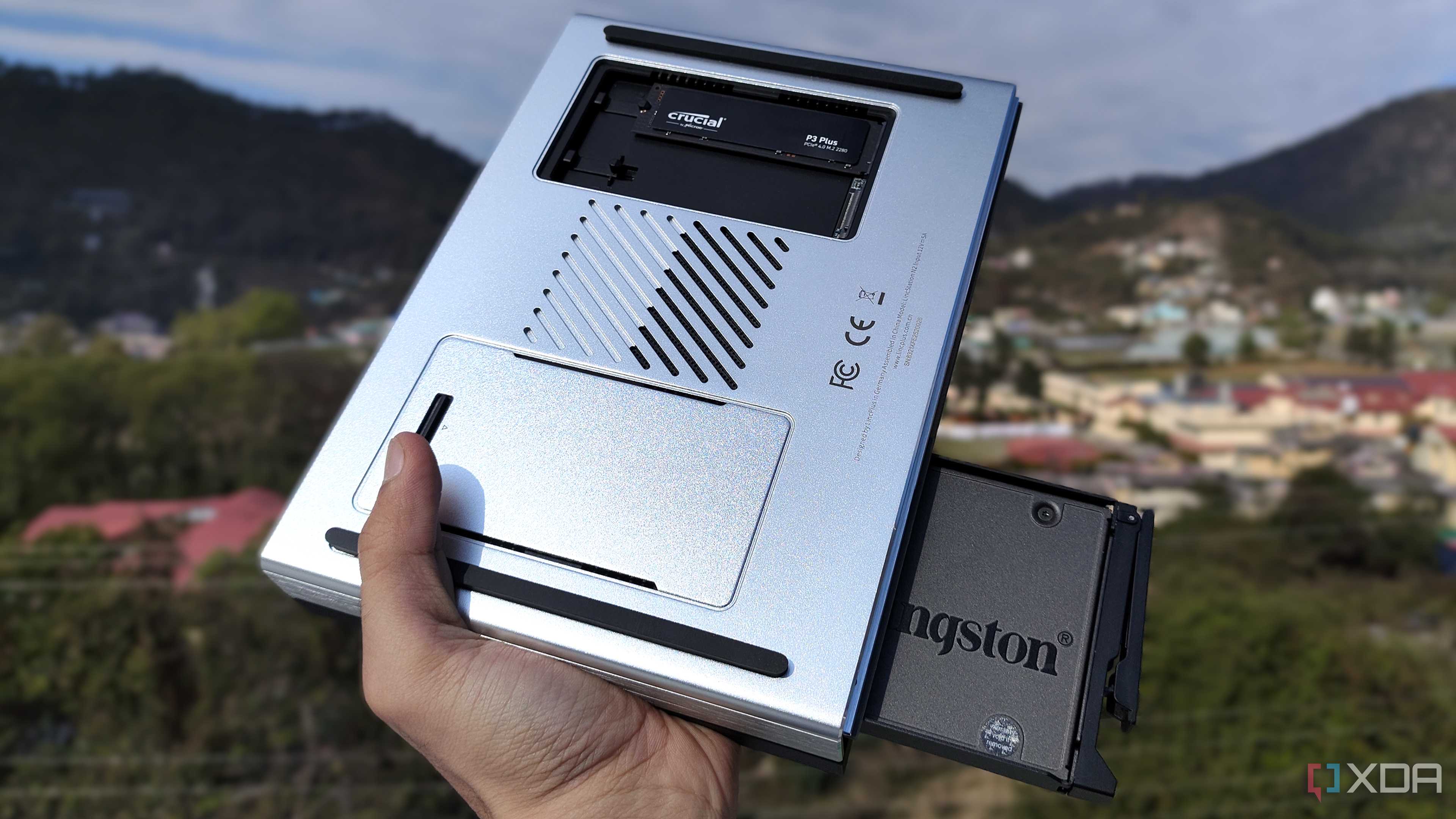 A person holding the LincPlus LincStation N2 NAS, with an SSD popping out of the NAS