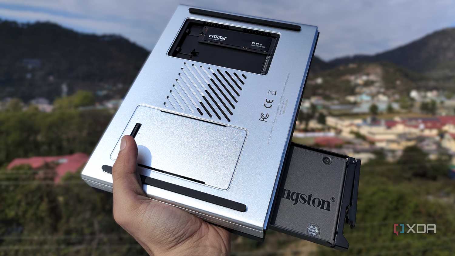 A person holding the LincPlus LincStation N2 NAS, with an SSD popping out of the NAS