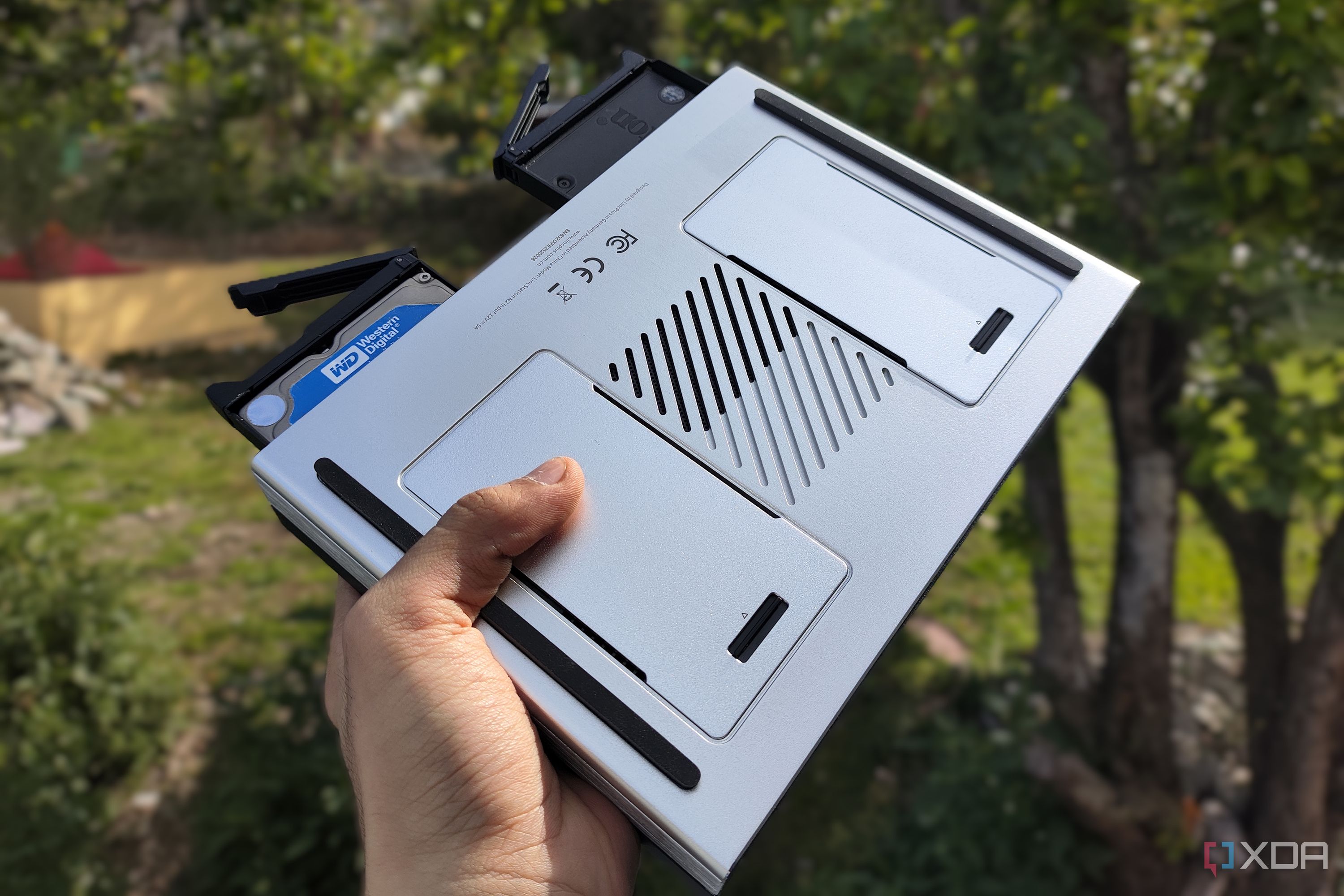 A person holding the LincPlus LincStation N2 NAS, with two drives popping out of the NAS