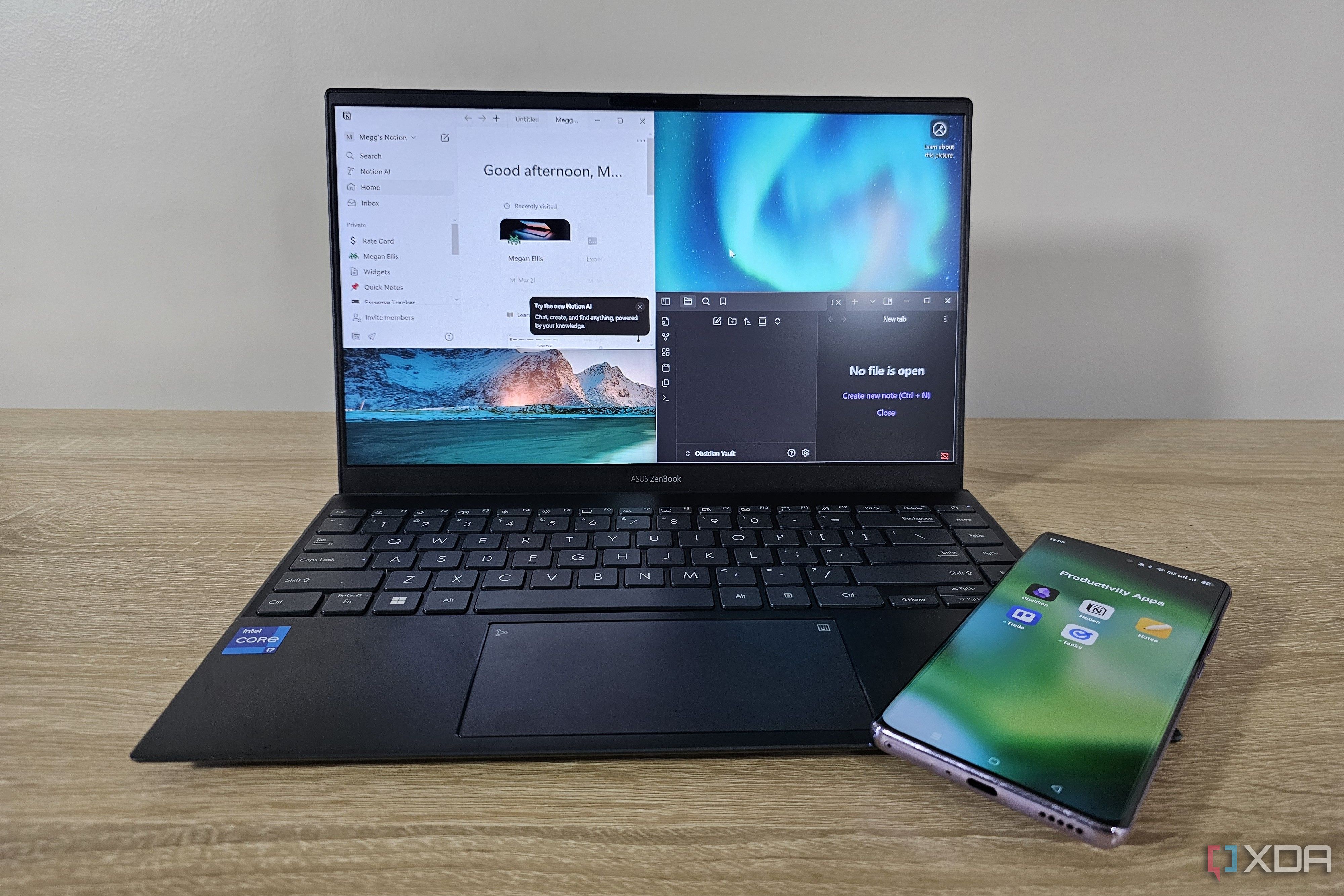 noción y obsidiana abiertos en una computadora portátil con un teléfono que muestra íconos de aplicaciones de productividad