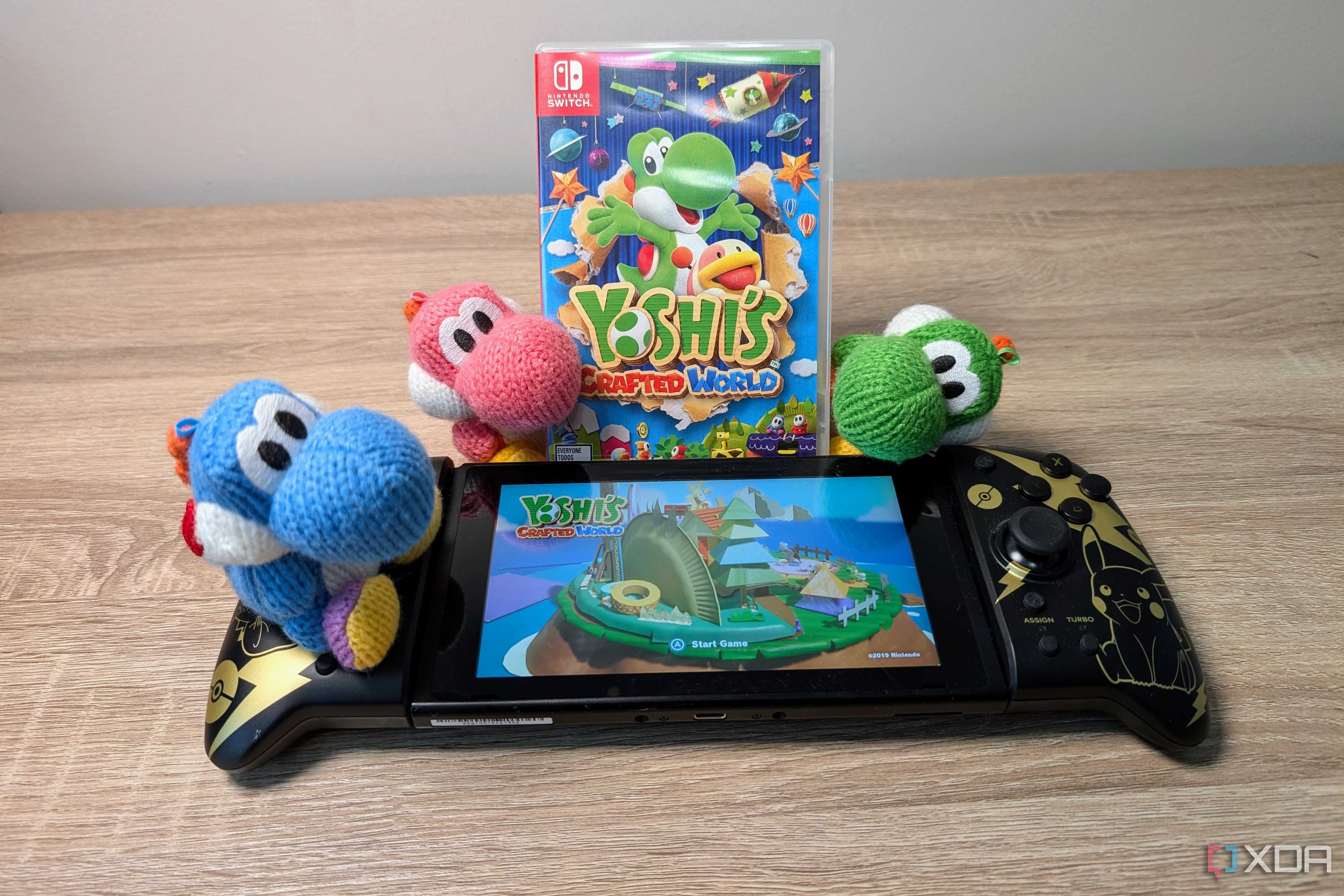 Three yarn Yoshis next to a Nintendo Switch featuring Yoshi's Crafted World