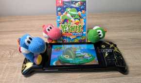 Three yarn Yoshis next to a Nintendo Switch featuring Yoshi's Crafted World