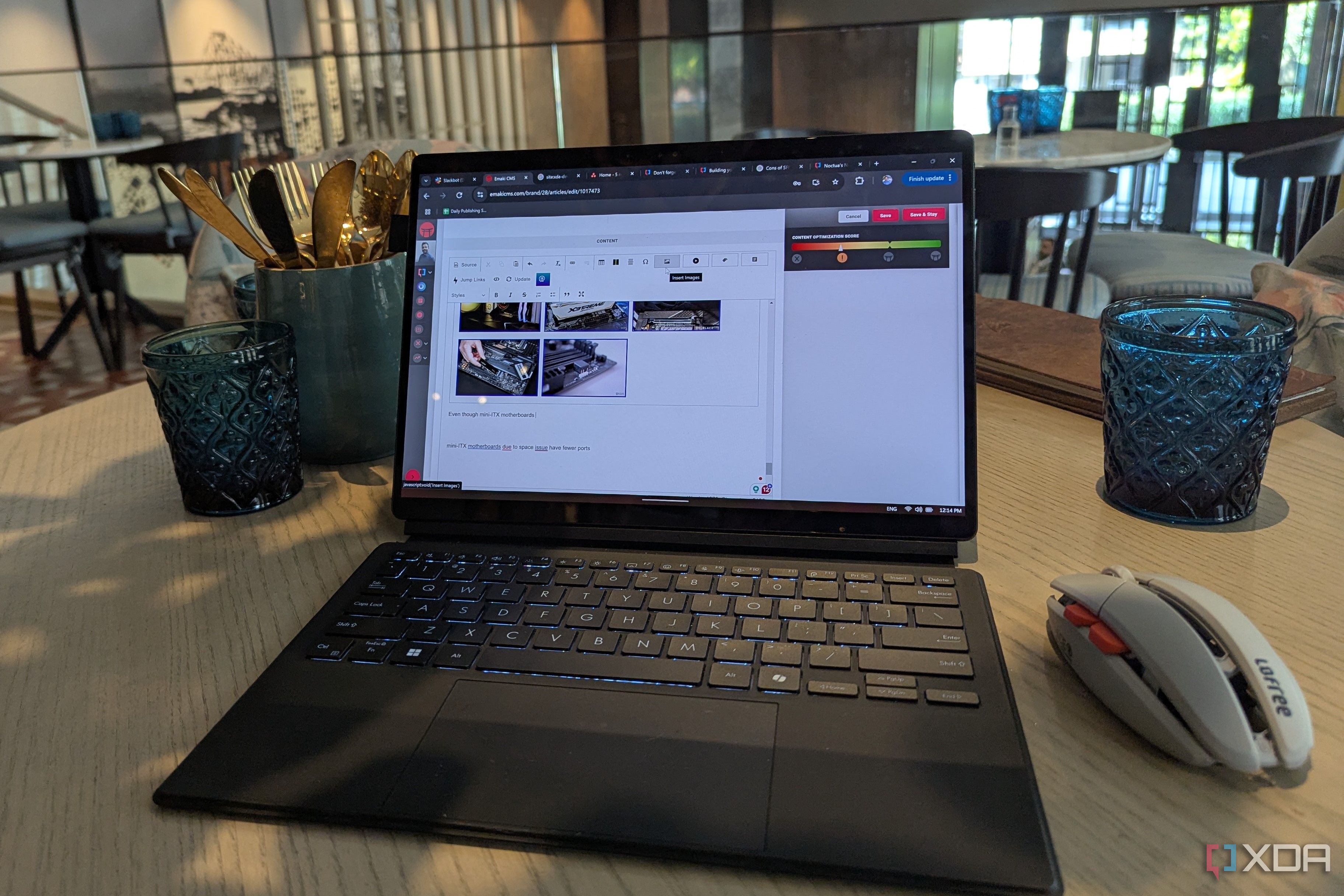 A black laptop and grey wireless mouse on a brown table