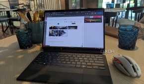 A black laptop and grey wireless mouse on a brown table