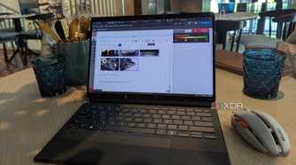 A black laptop and grey wireless mouse on a brown table