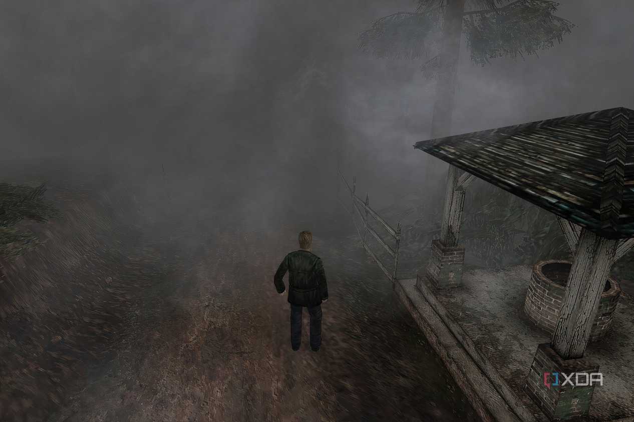 An in-game screenshot from the game Silent Hill 2, showing a man standing next to a dilapidated gazebo while surrounded by thick fog.