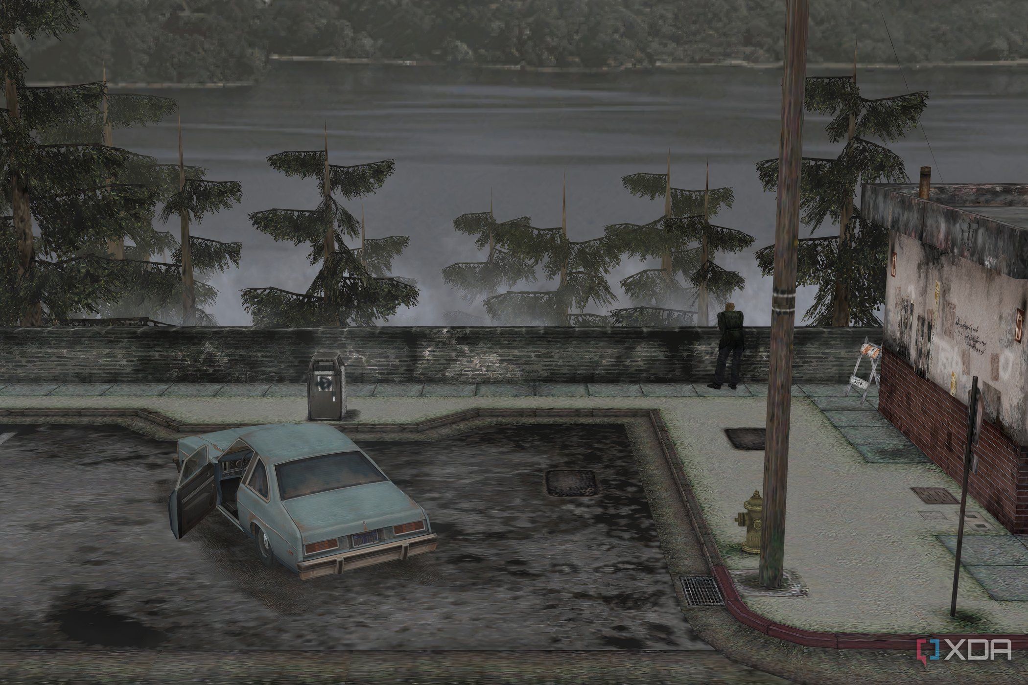 An in-game screenshot from the game Silent Hill 2, showing a large lake, a parking lot, and a blue coupe.