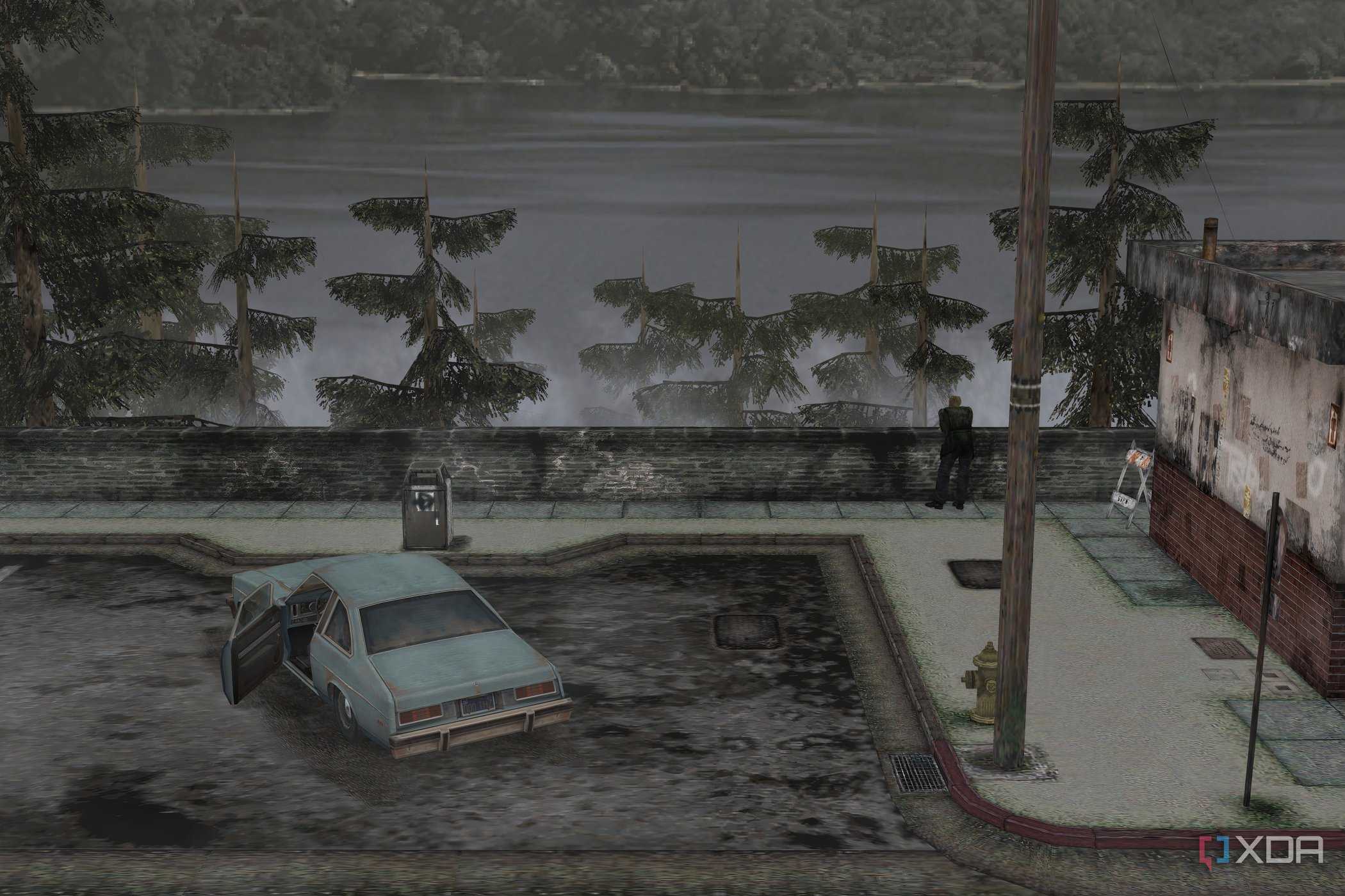 An in-game screenshot from the game Silent Hill 2, showing a large lake, a parking lot, and a blue coupe.