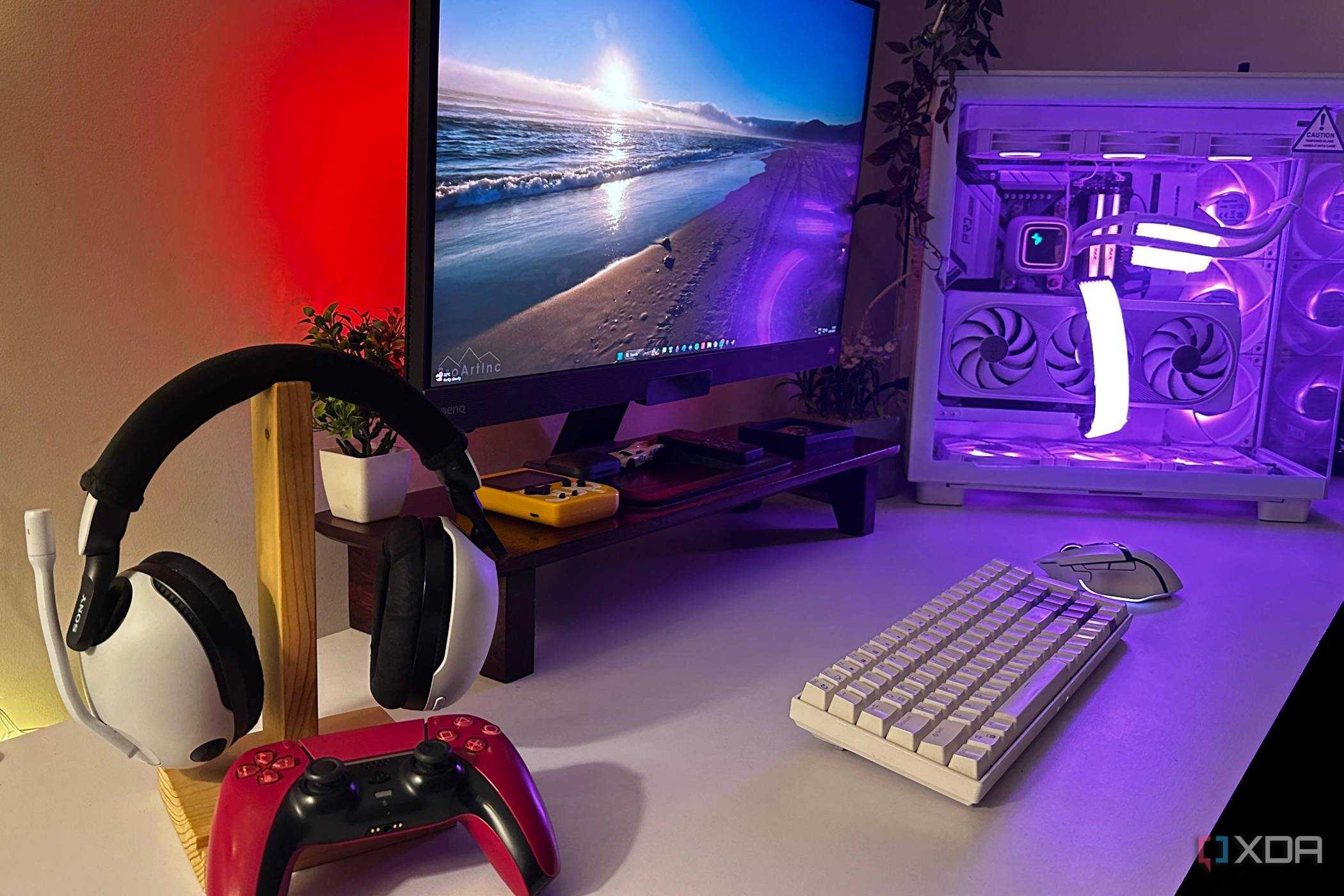 White Sony Inzone headsets with Cosmic Red DualSense controller sat on a desk with a gaming PC.