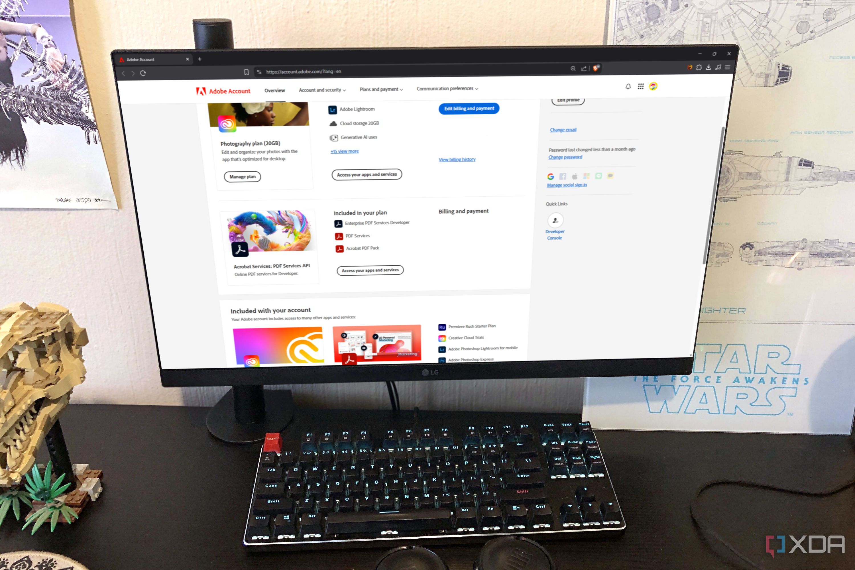 Adobe website displayed on desktop pc, with headphones, poster, and lego in view