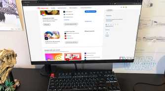 Adobe website displayed on desktop pc, with headphones, poster, and lego in view