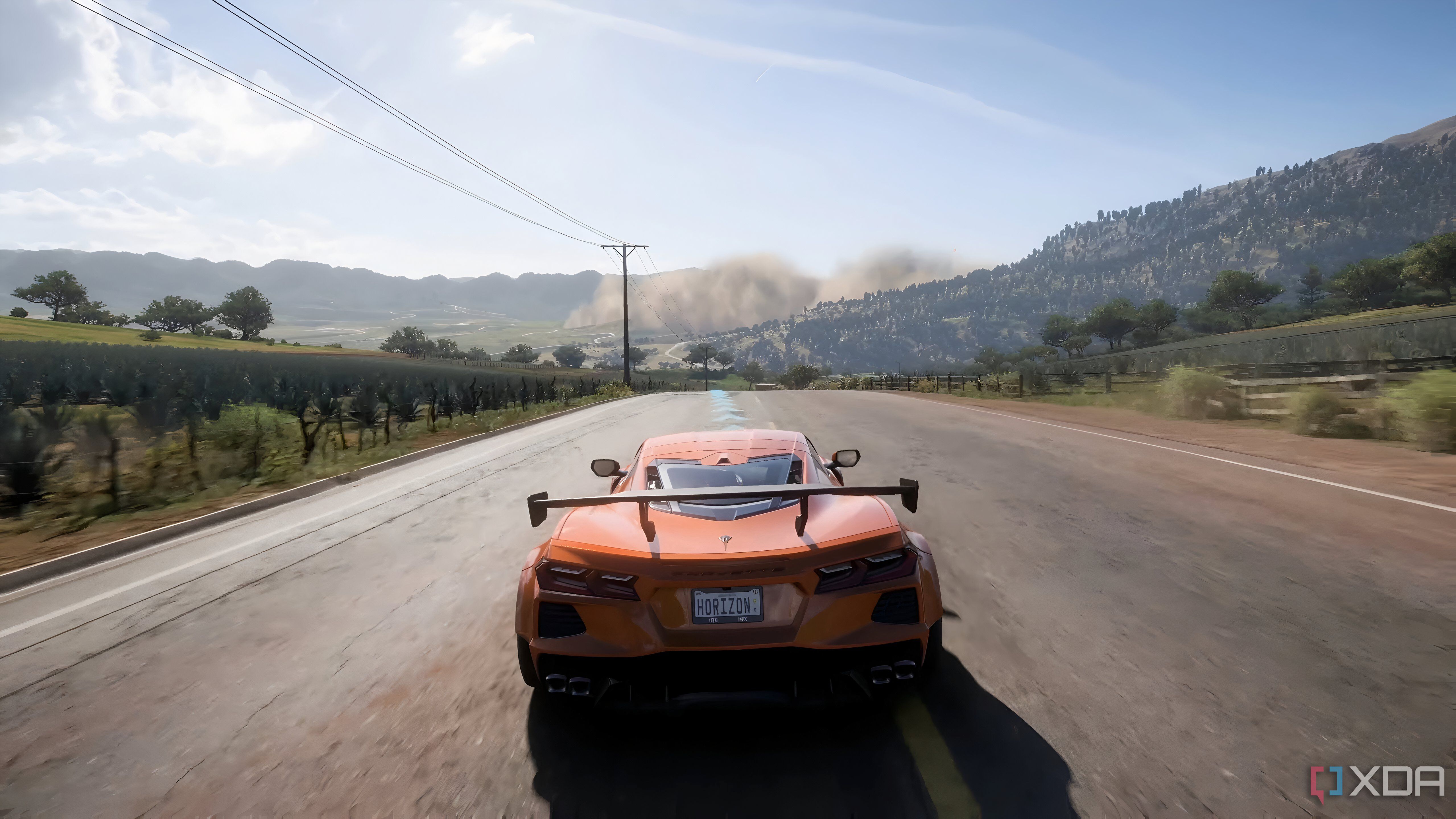 The opening of Forza Horizon 5, showing an orange Corvette C8 Stingray speeding down a road.