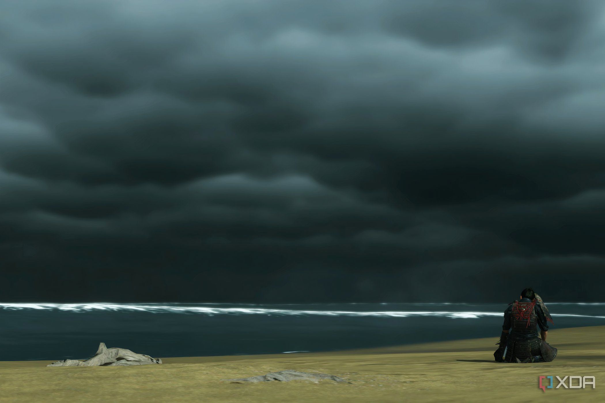 A screenshot from Ghost of Tsushima, showing Jin defeatedly sitting at Komoda beach, alone.