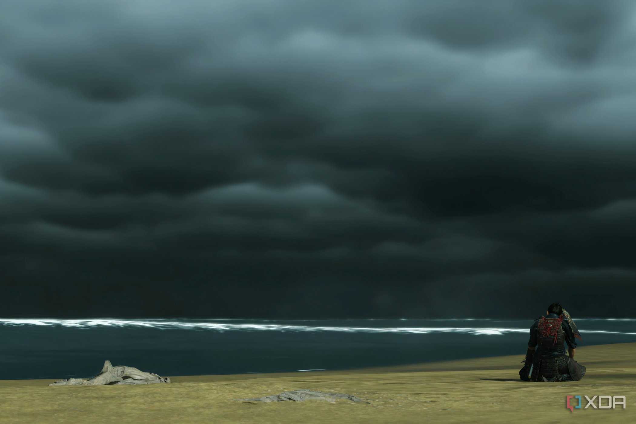 A screenshot from Ghost of Tsushima, showing Jin defeatedly sitting at Komoda beach, alone.