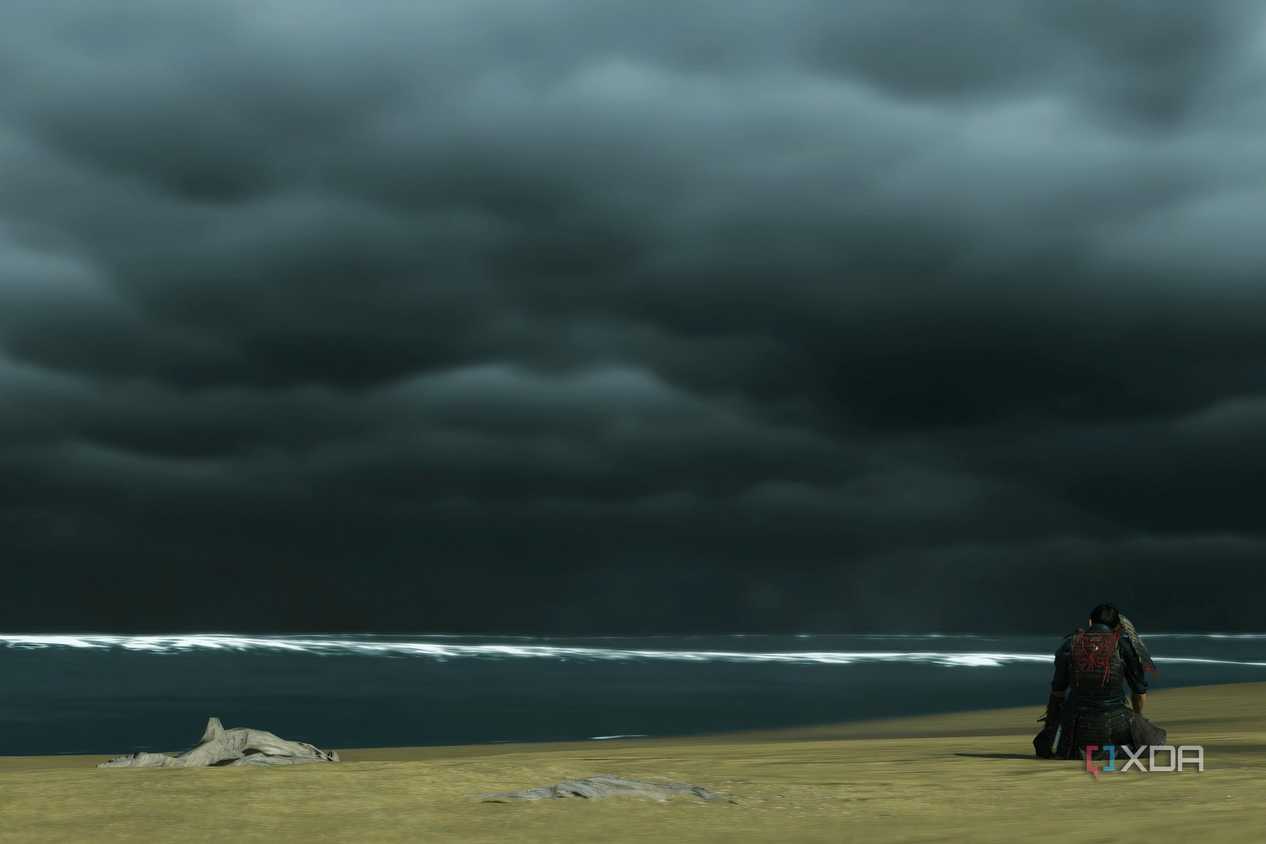 A screenshot from Ghost of Tsushima, showing Jin defeatedly sitting at Komoda beach, alone.