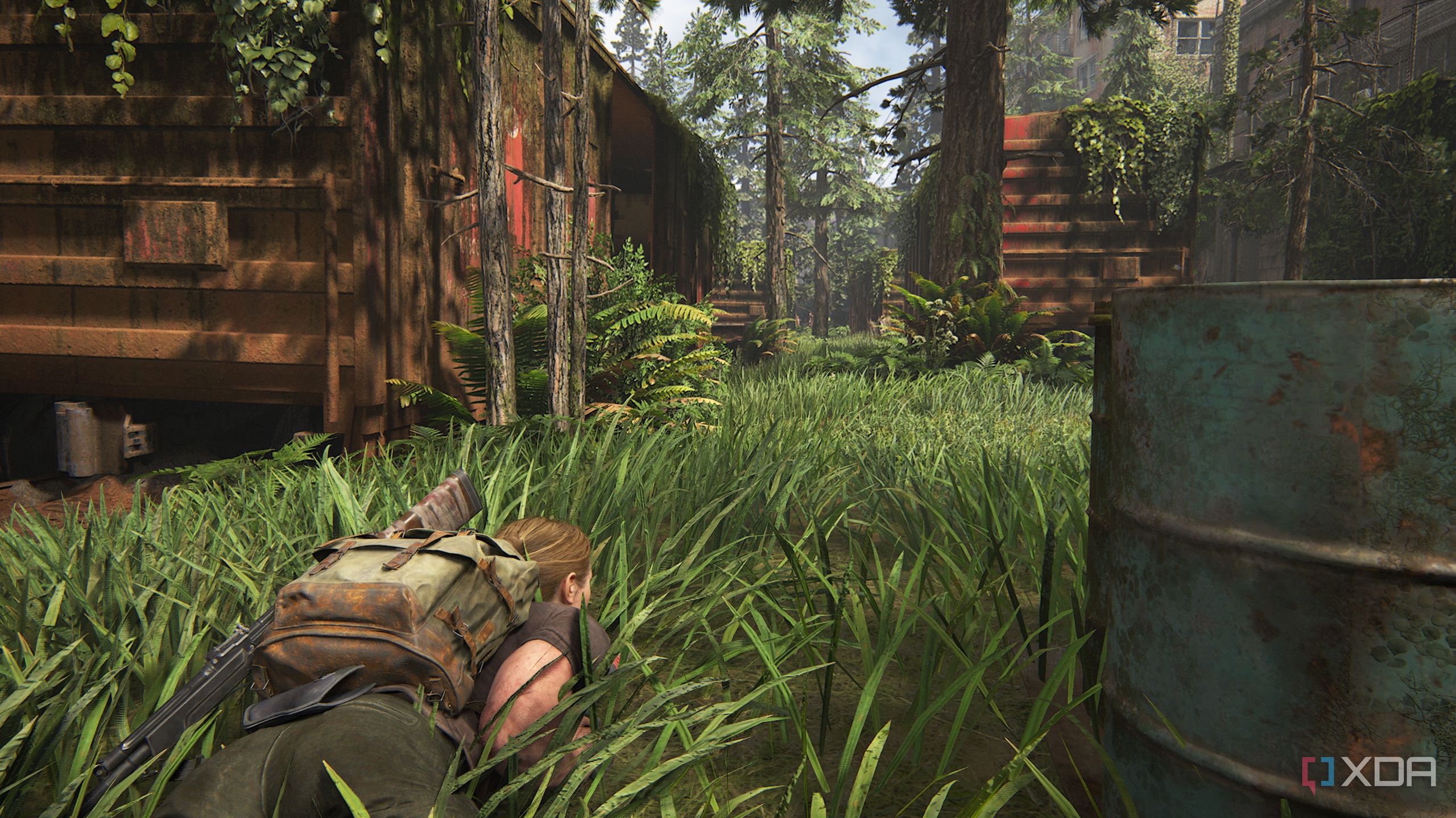 A screenshot from the game The Last of Us Part II, showing Abby prone in grass.