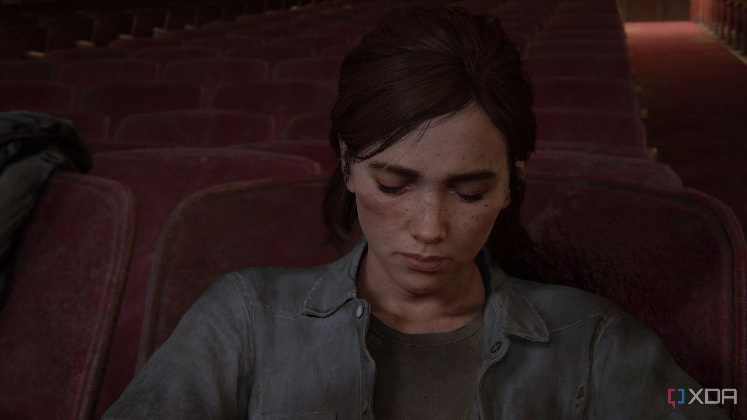 A screenshot from the game The Last of Us Part II, showing Ellie asleep on a theatre seat.