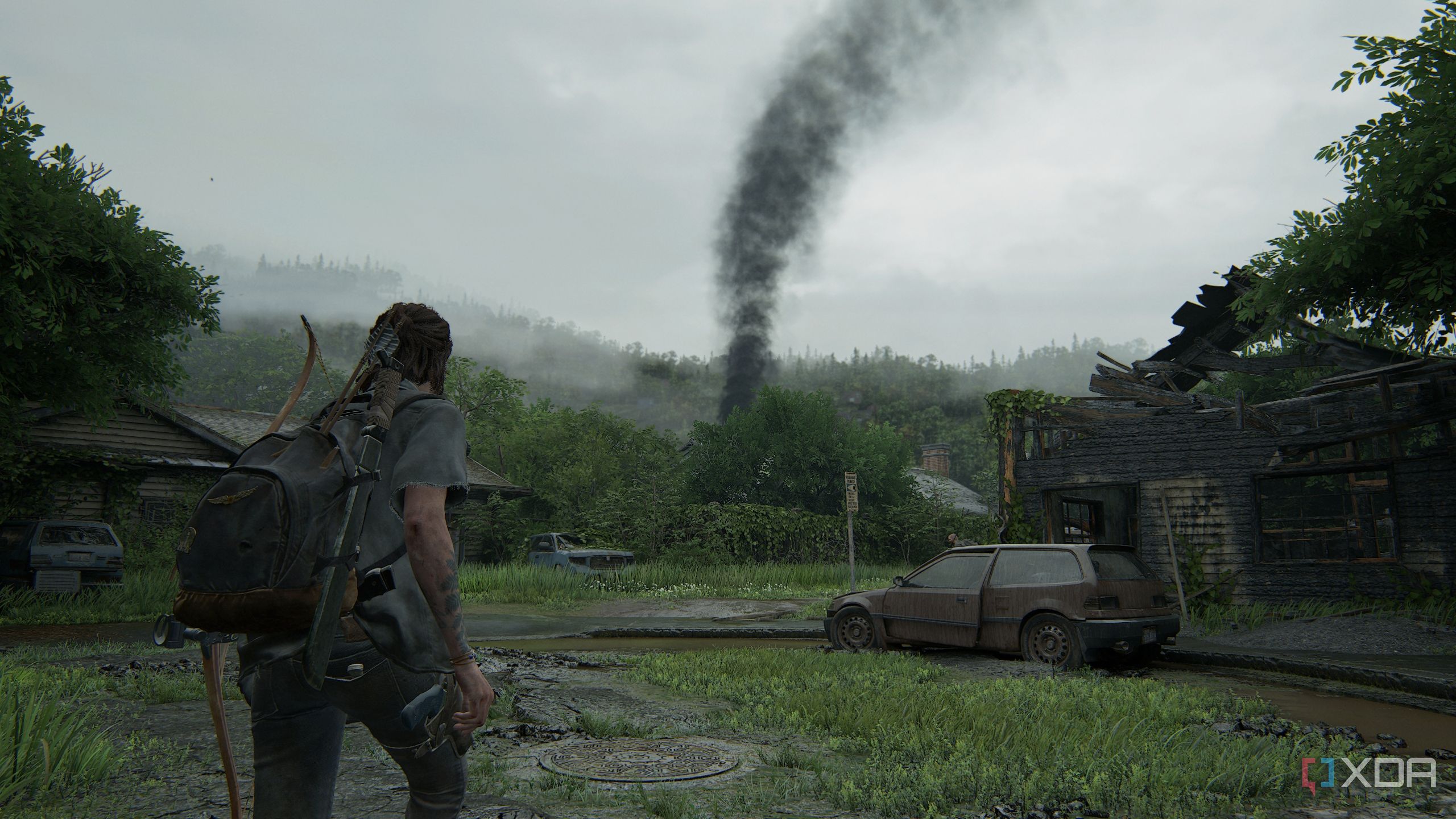 A screenshot from the game The Last of Us Part II, showing Ellie looking at black smoke blowing from a distance.