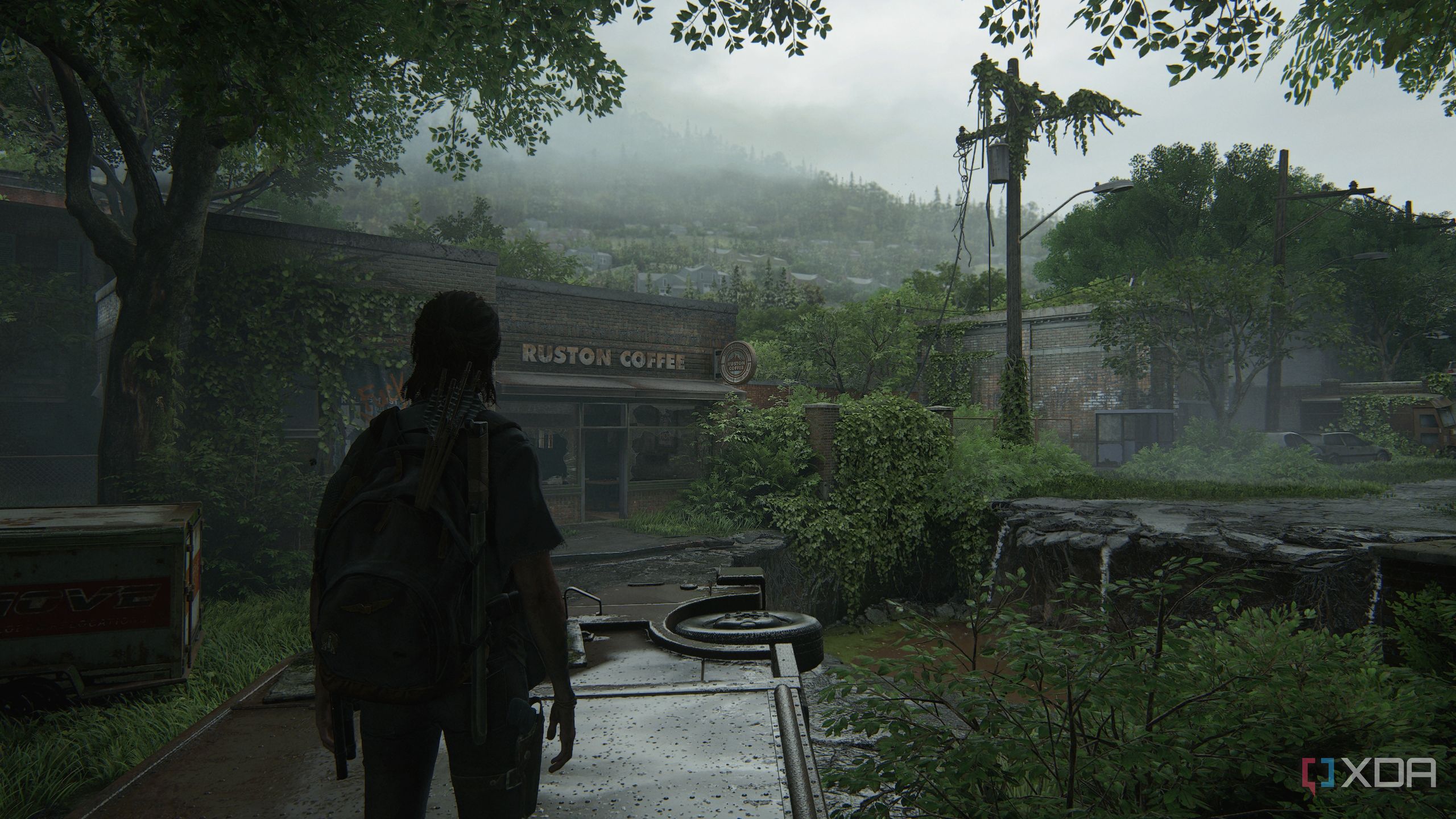 A screenshot from the game The Last of Us Part II, showing Ellie standing on an overturned vehicle.