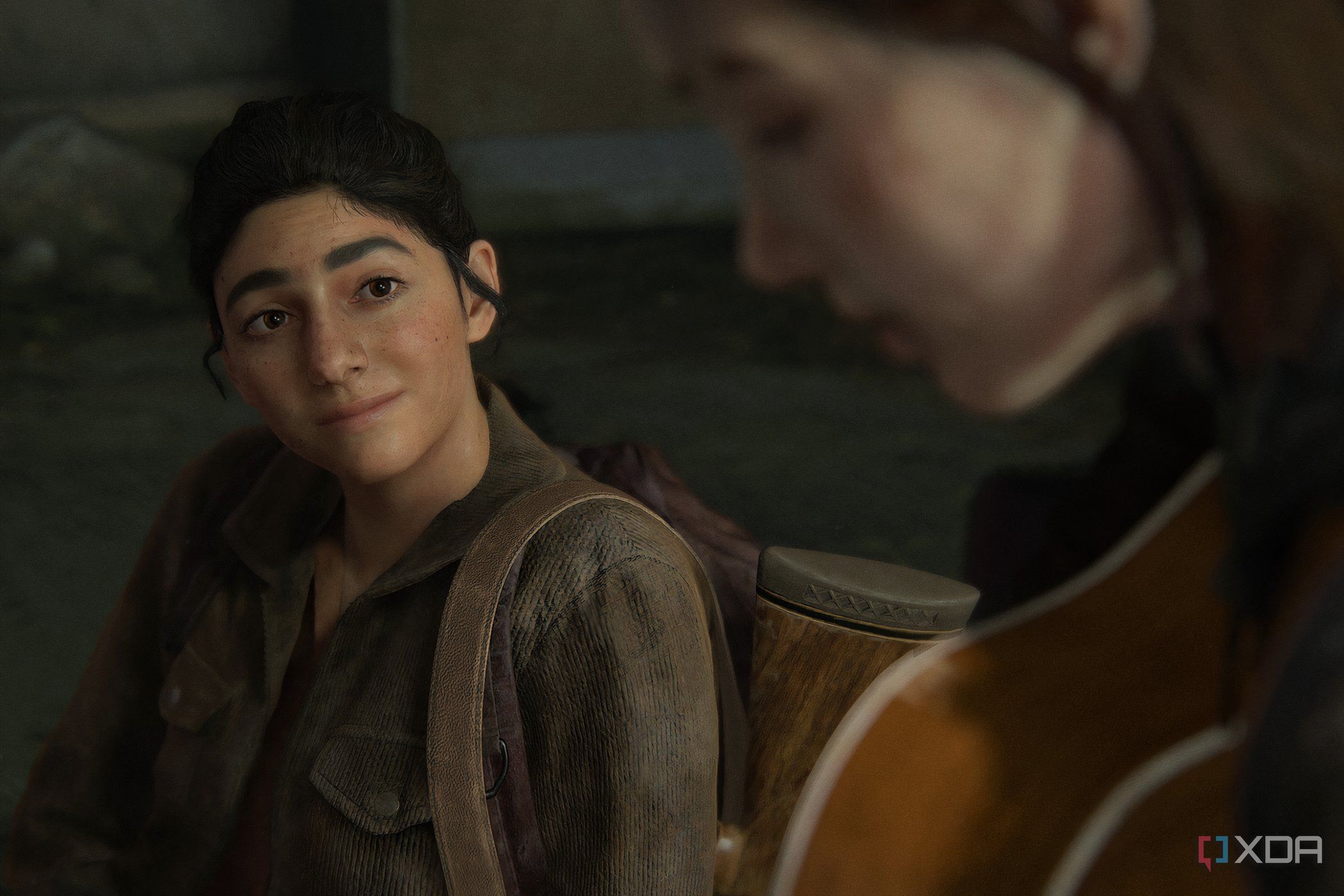 A screenshot from The Last of Us Part II, showing Dina looking at Ellie play the guitar.