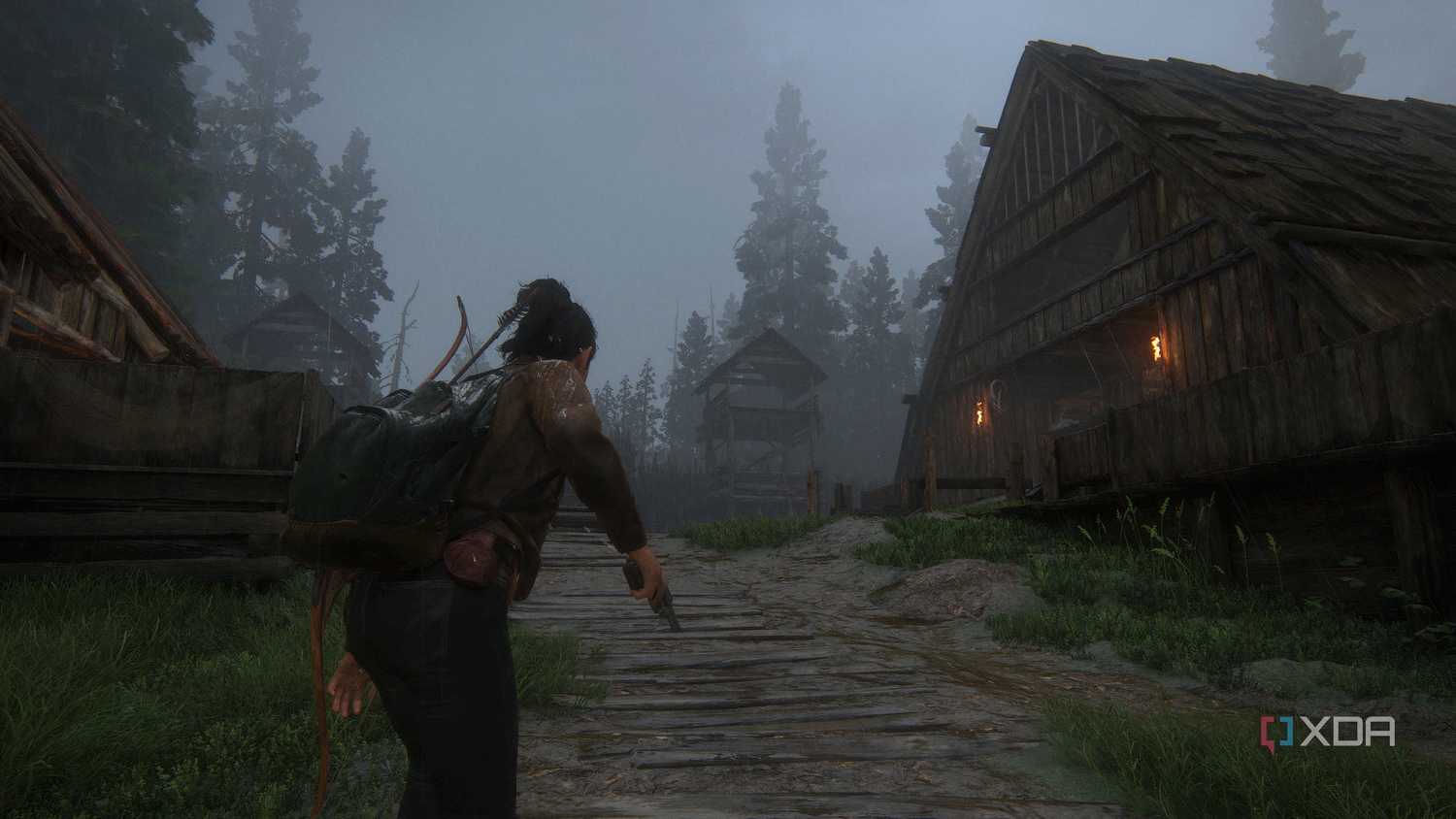 A screenshot from the game The Last of Us Part II Remastered on PC, showing Dina wielding a pistol near wooden houses.