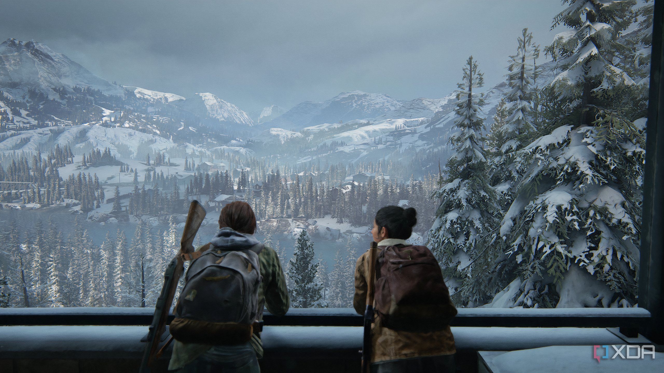 A screenshot from the game The Last of Us Part II Remastered on PC, showing Ellie and Dina leaning against a balcony railing, taking in a snowy mountaineous landscape.