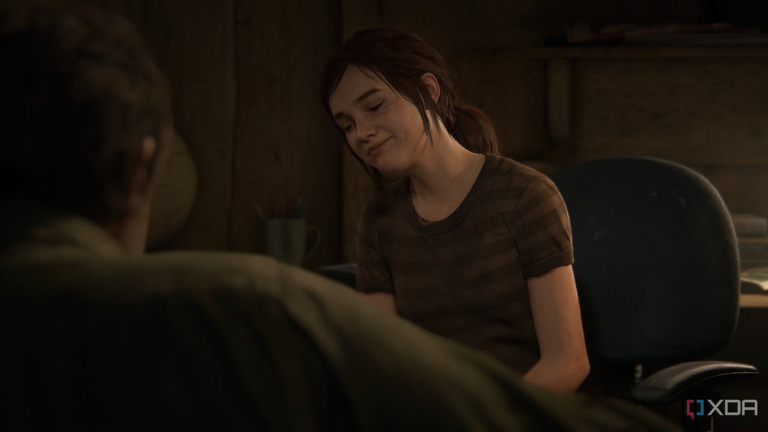A screenshot from the game The Last of Us Part II Remastered on PC, showing a young Ellie sitting on a chair.
