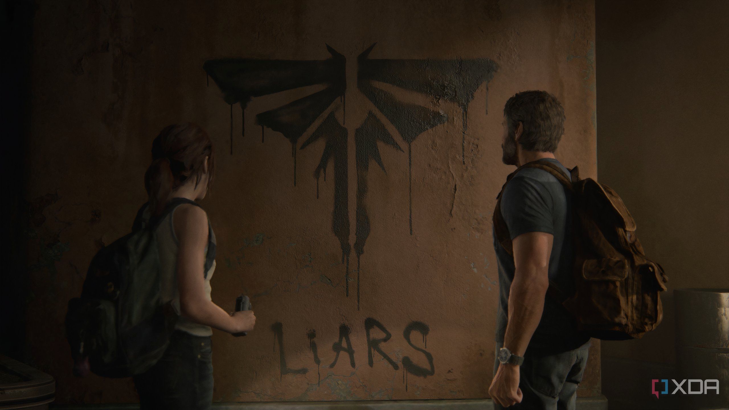 A screenshot from the game The Last of Us Part II Remastered on PC, showing Joel and Ellie looking at the Fireflies logo painted on a wall.