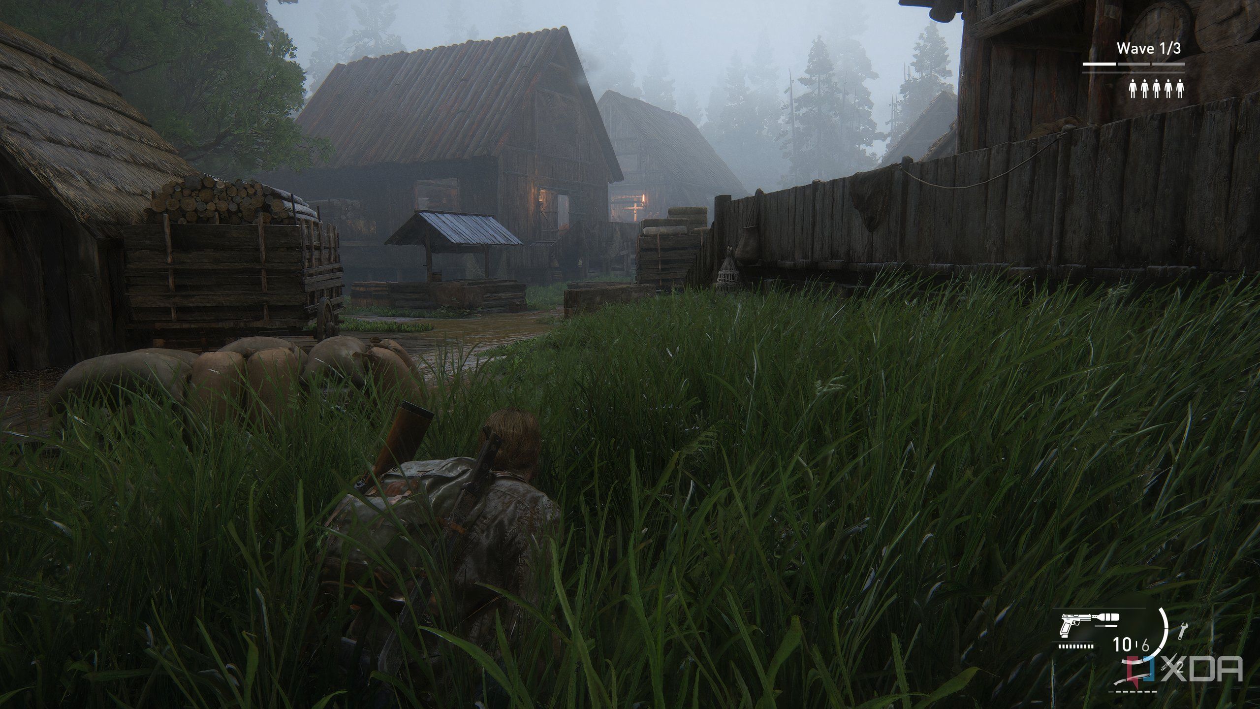 A screenshot from the game The Last of Us Part II Remastered on PC, showing Bill crawling through grass near mist-laden wooden houses.