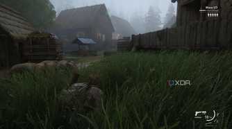 A screenshot from the game The Last of Us Part II Remastered on PC, showing Bill crawling through grass near mist-laden wooden houses.