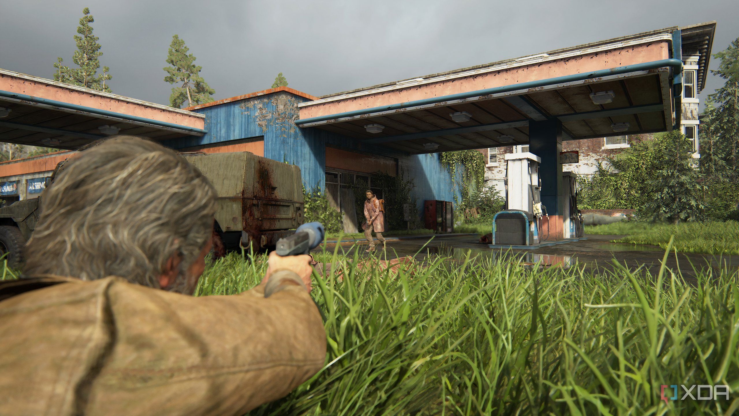 A screenshot from the game The Last of Us Part II Remastered on PC, showing Joel proning in grass and aiming at an enemy.