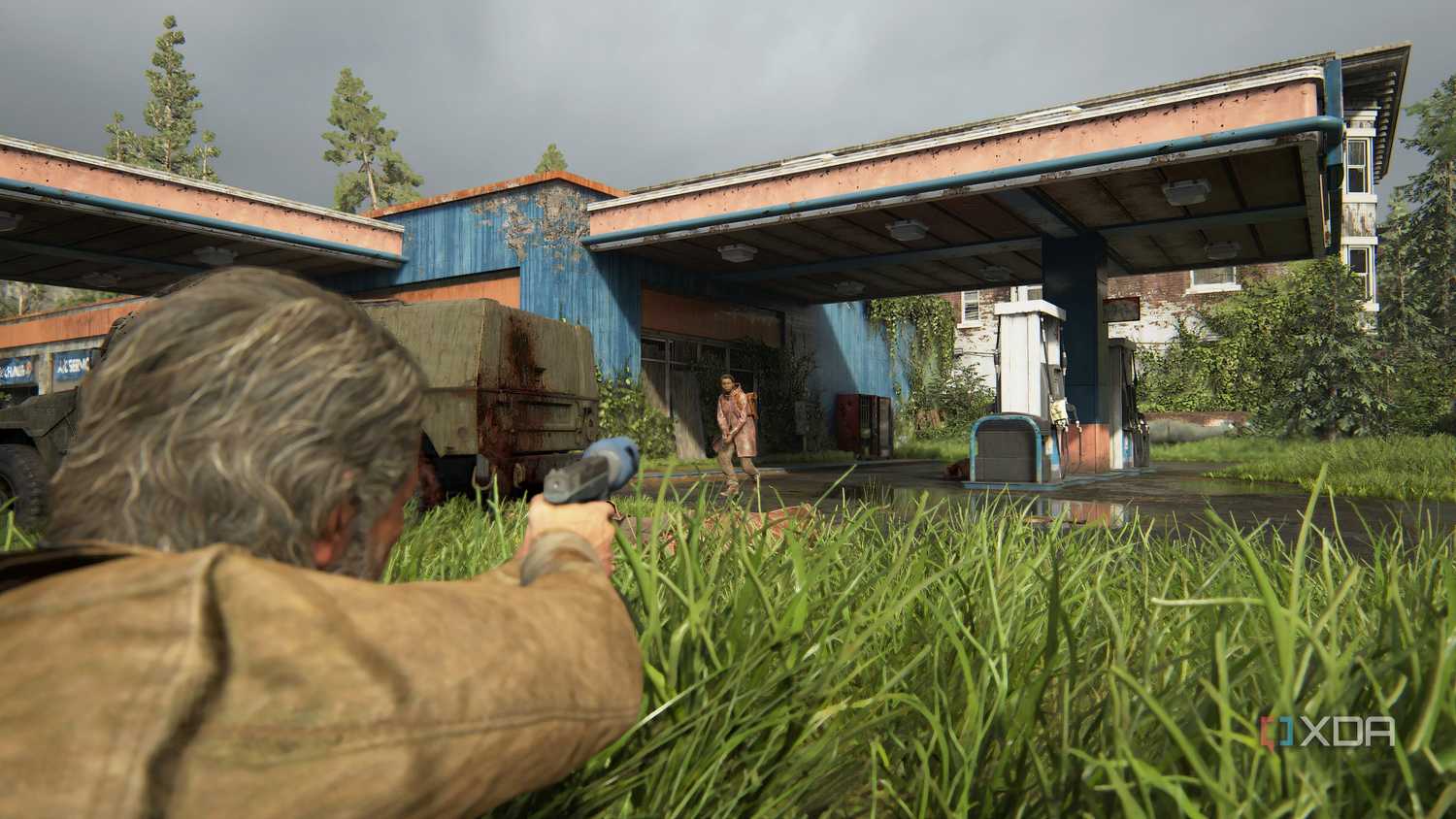 A screenshot from the game The Last of Us Part II Remastered on PC, showing Joel proning in grass and aiming at an enemy.