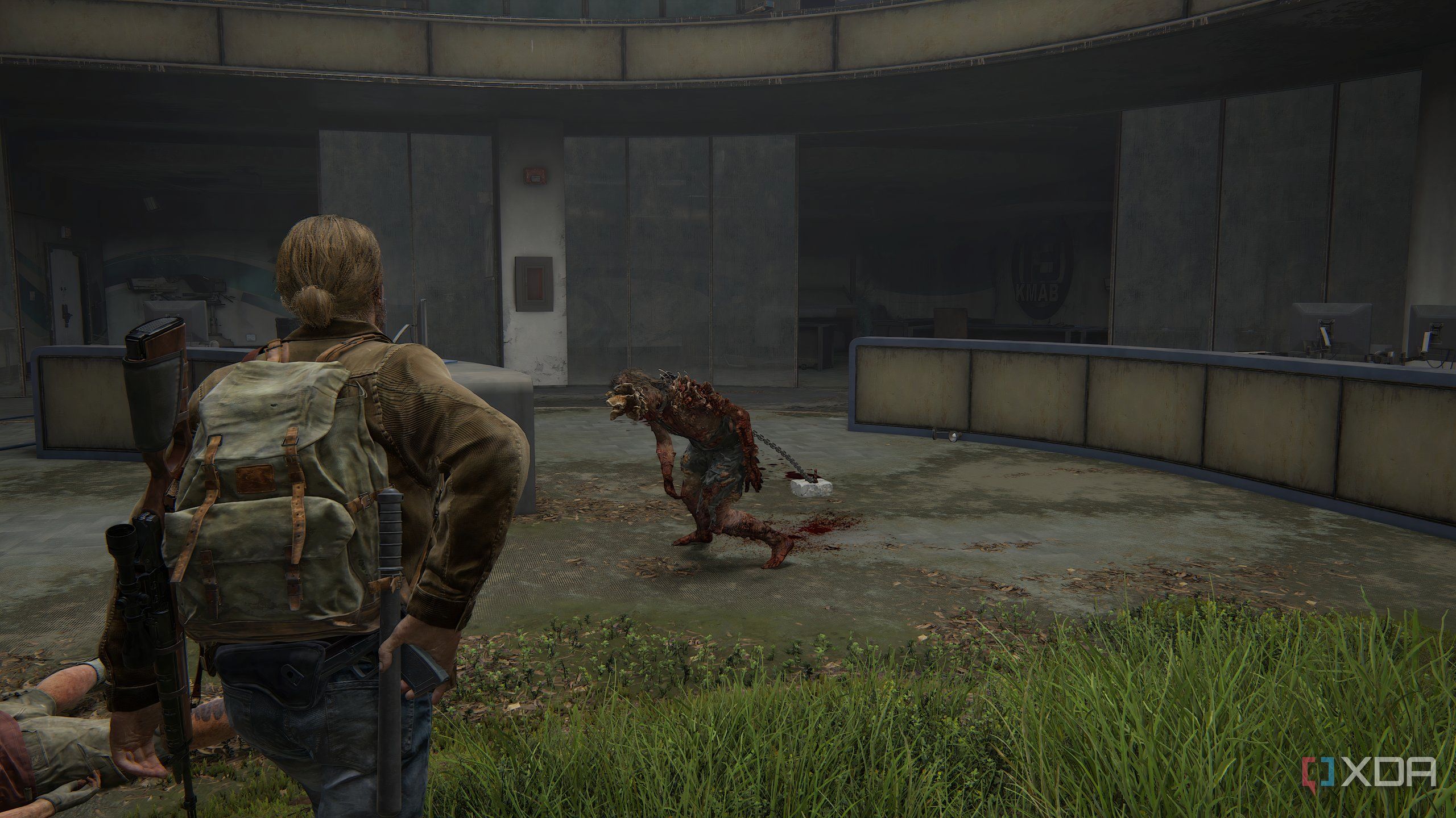 A screenshot from the game The Last of Us Part II Remastered on PC, showing Tommy taking out a gun while walking up to a chained clicker zombie.